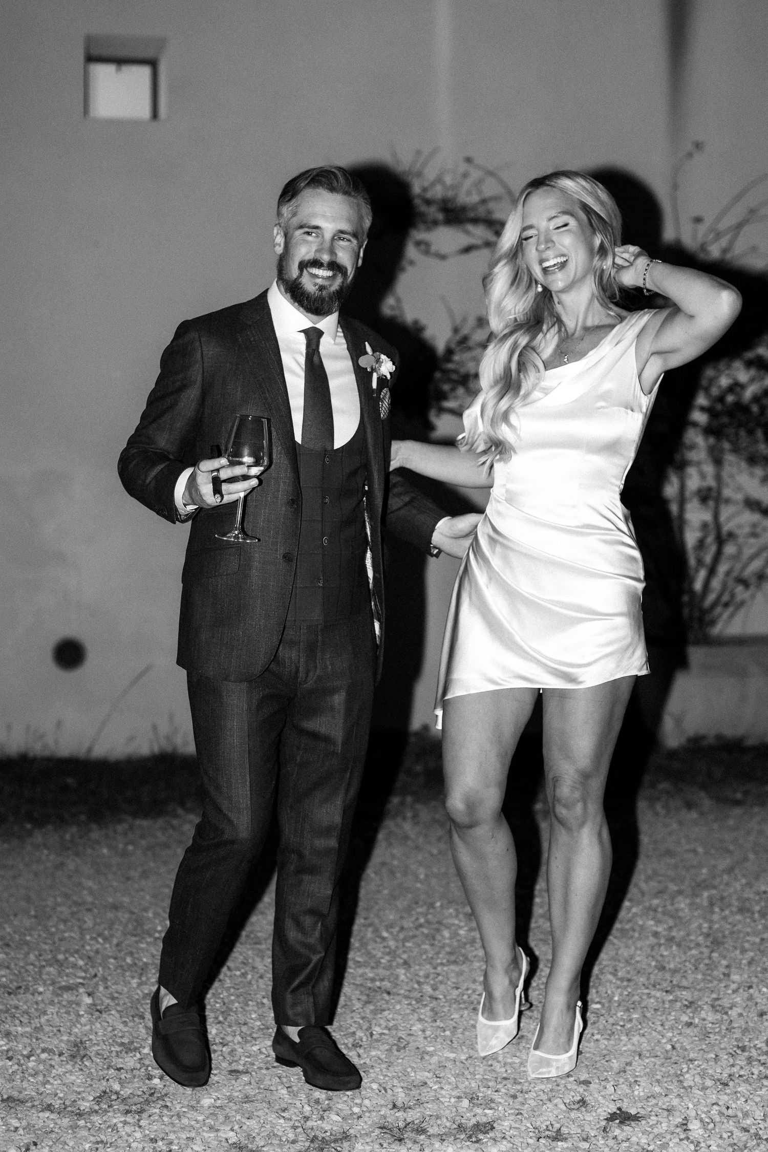 Black and white photos capture playful dance moves on a gravel path at night with stone walls in the background.