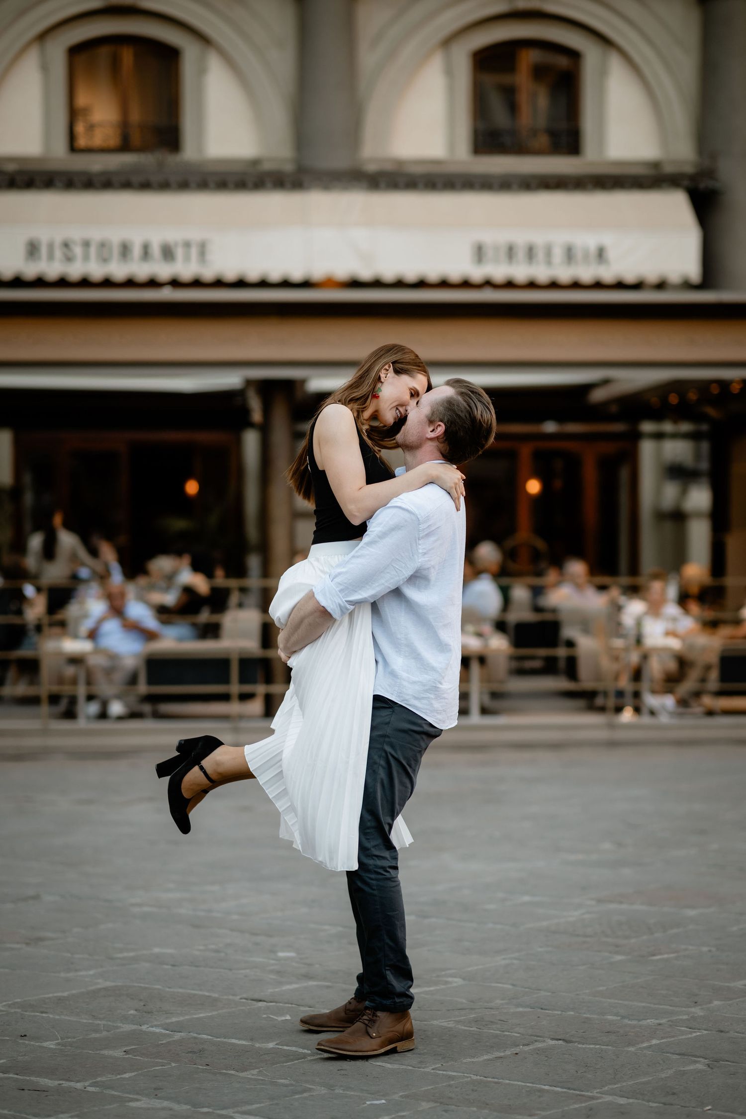 A romantic moment between a couple sharing an intimate embrace outside an Italian ristorante in a charming urban setting.