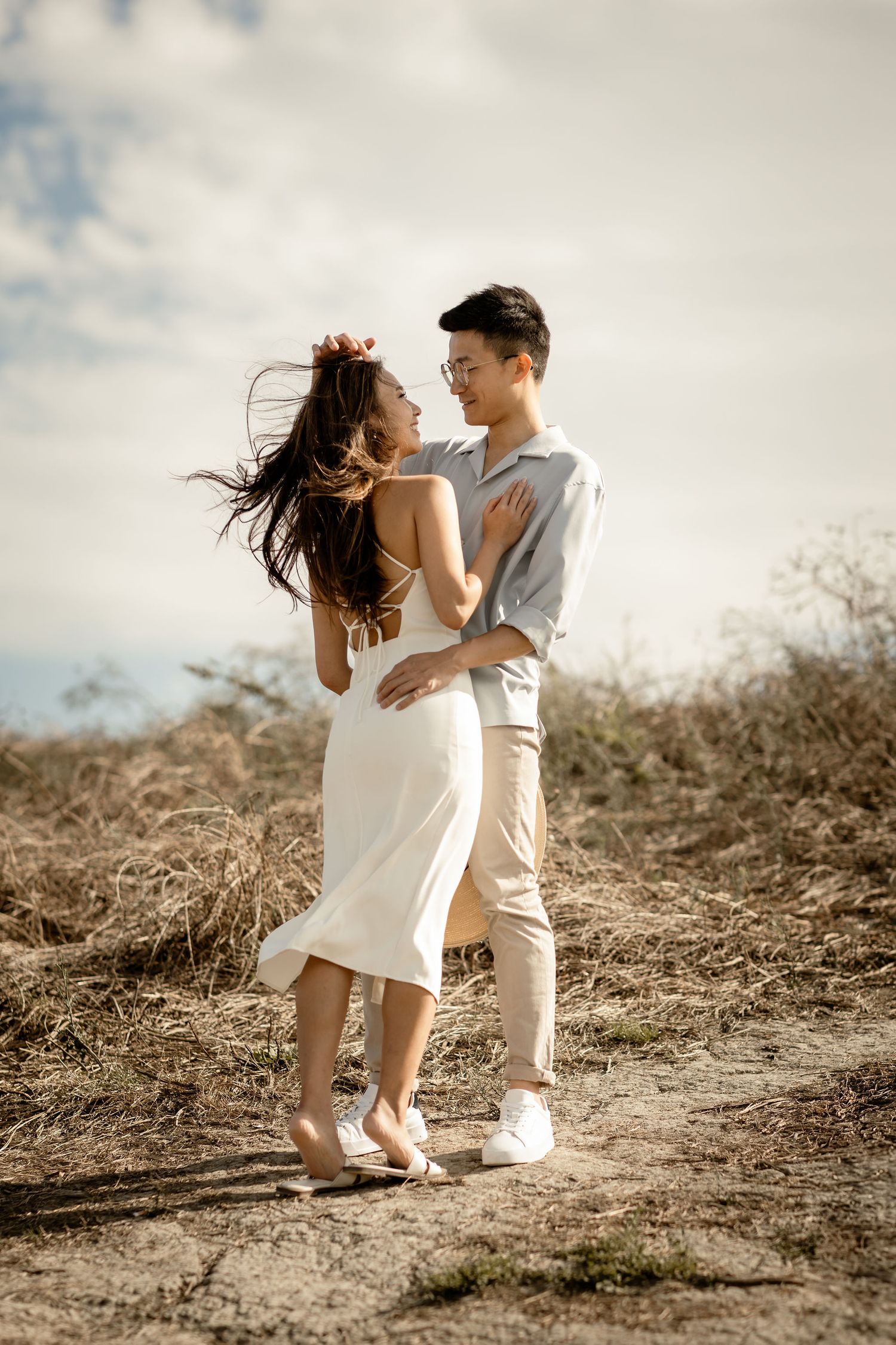 A romantic dance pose on a hilltop trail with flowing hair and casual elegant outfits.