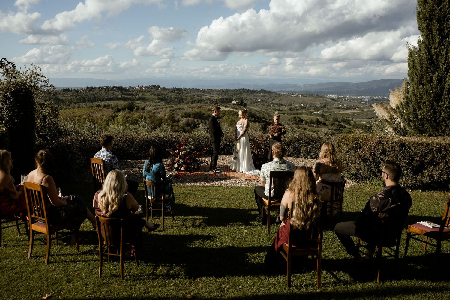 People enjoy a scenic view of rolling hills and countryside from an elevated outdoor viewing area on a sunny day.