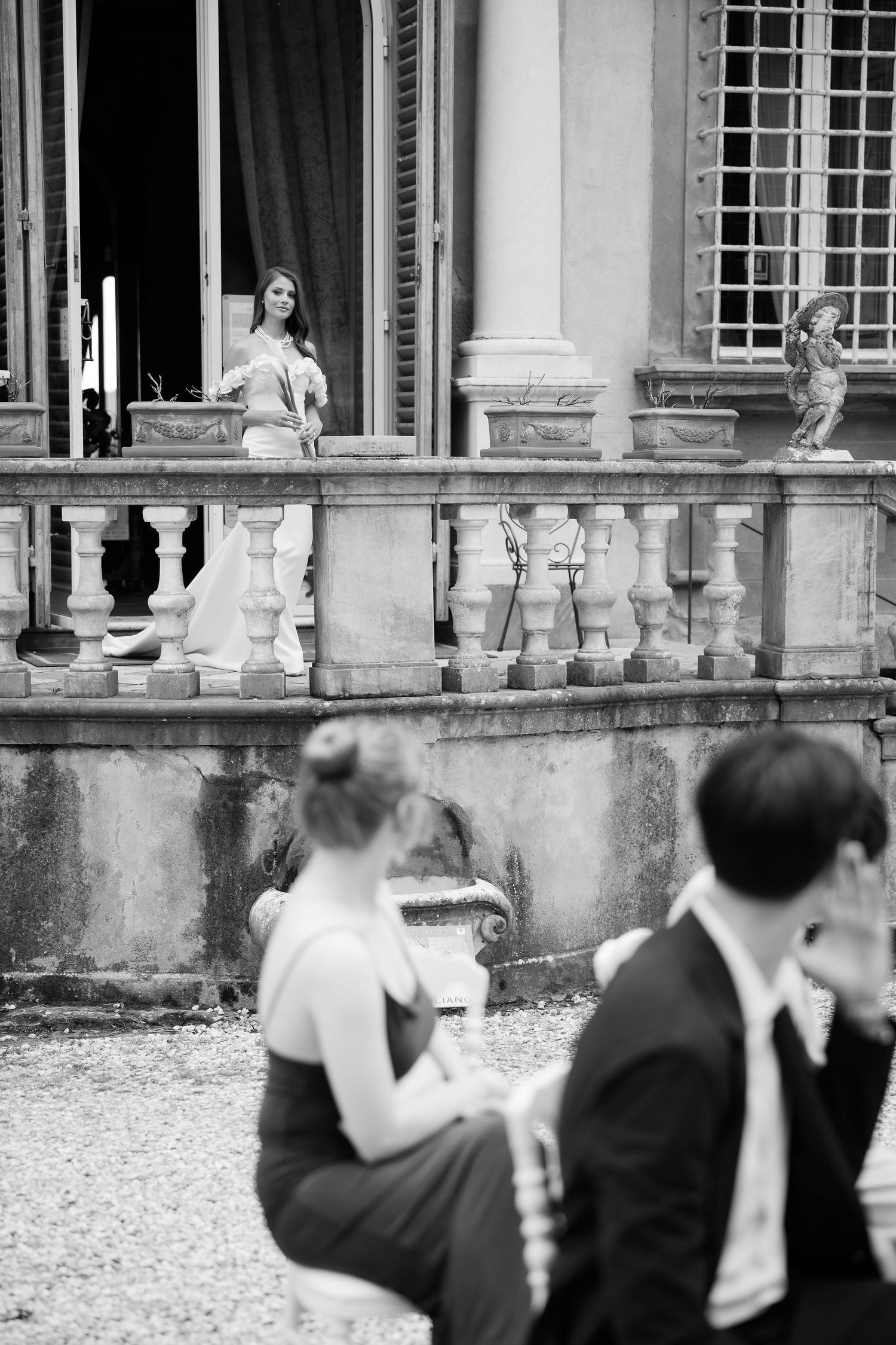 A vintage black and white photo showing an elegant balcony with stone balustrades at a classical European building.