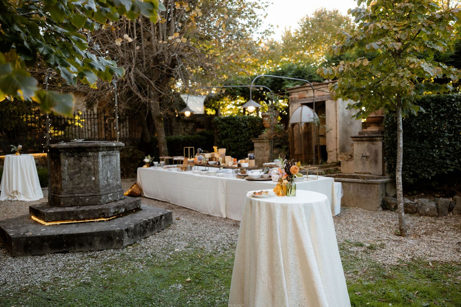 Elegant outdoor wedding reception setup with round tables covered in white linens and floral centerpieces at sunset.