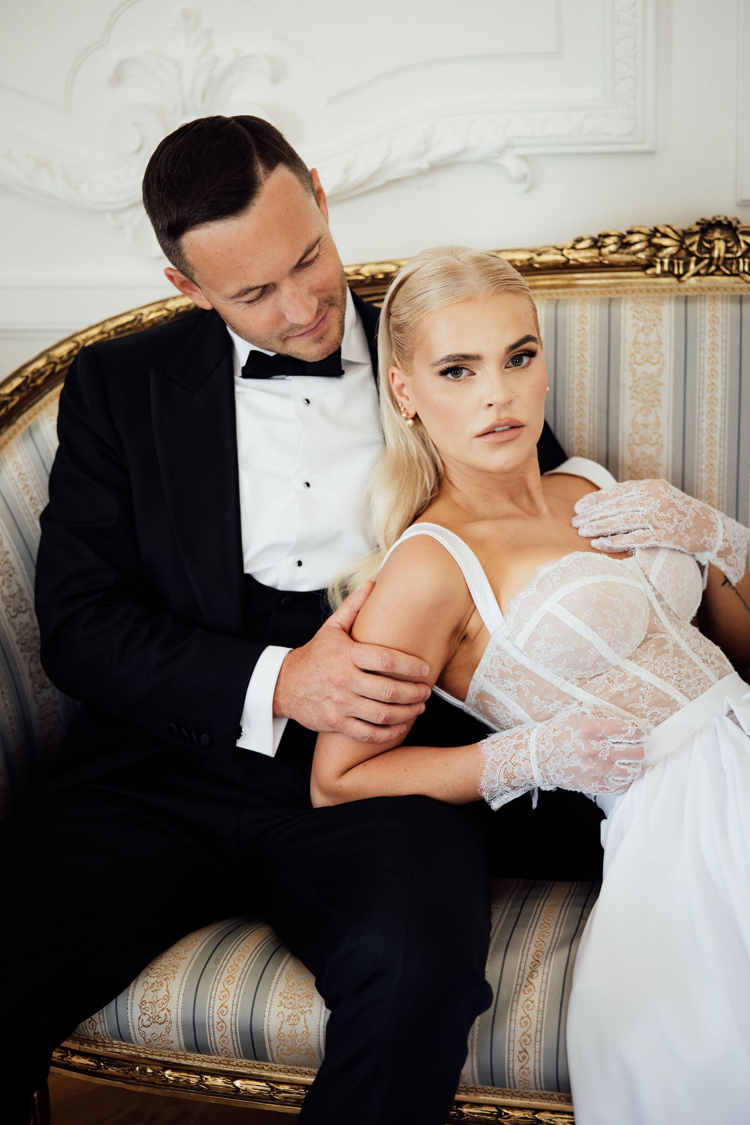 Intimate portrait of couple on vintage sofa in elegant formal attire.
