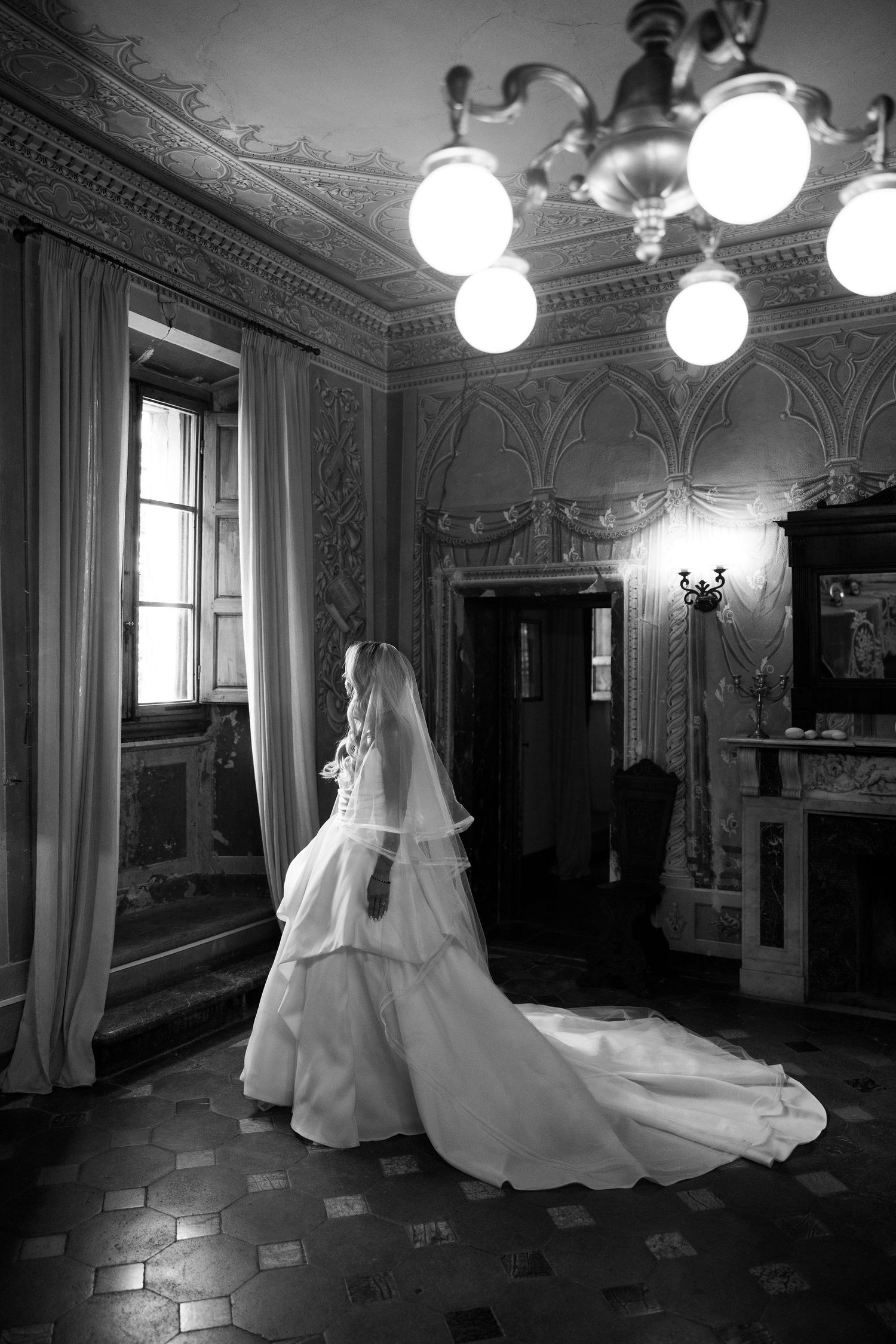 A black and white photo series showing a wedding dress in an ornate room with vintage decor and globe lighting fixtures.