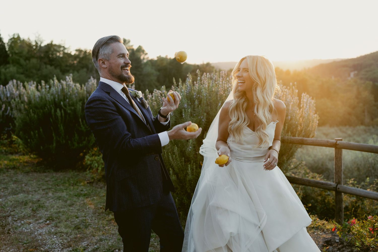 A couple shares an intimate sunset moment in a rustic outdoor setting with golden light filtering through the trees.