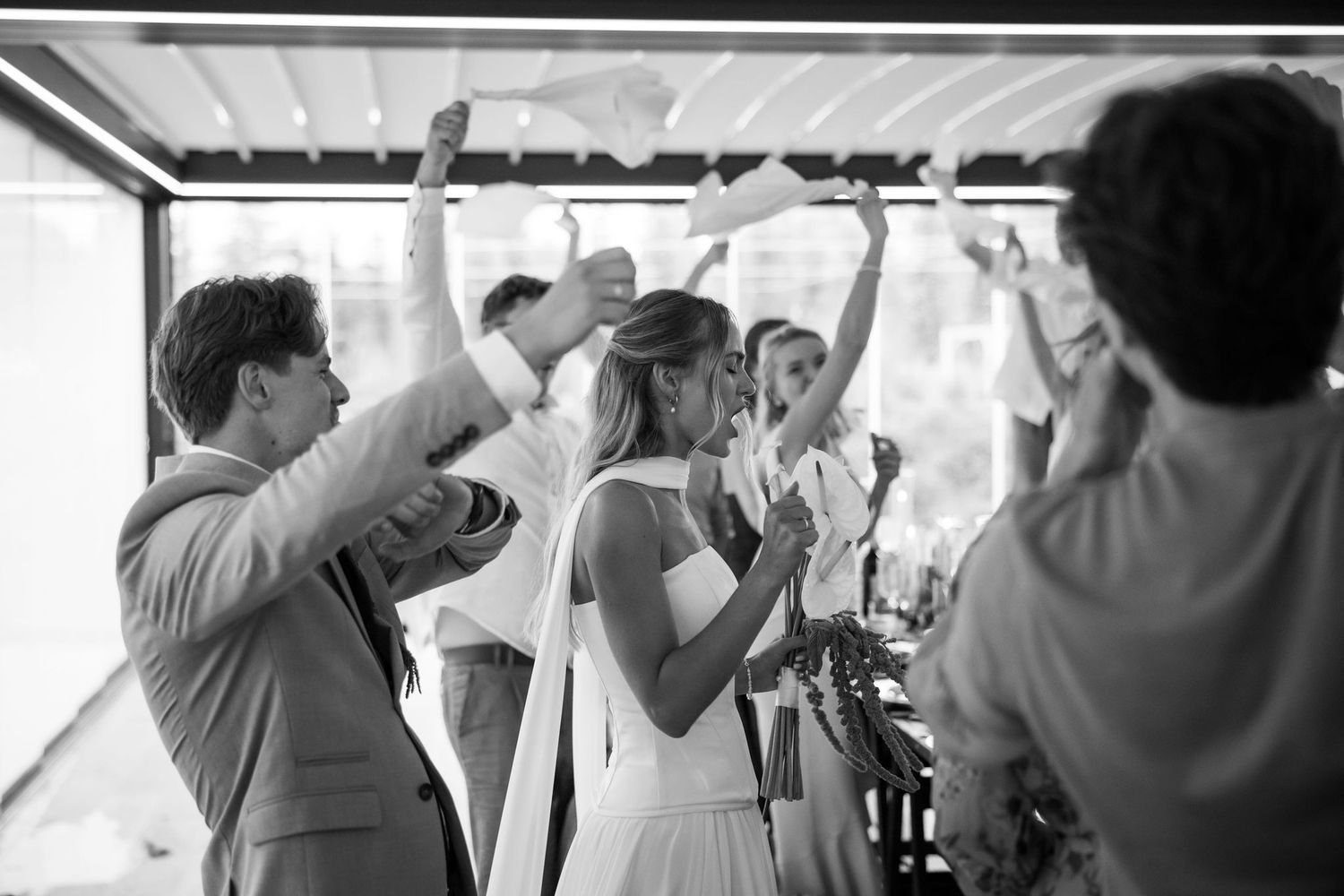Wedding guests dance and celebrate together on a reception dance floor under a white tent.