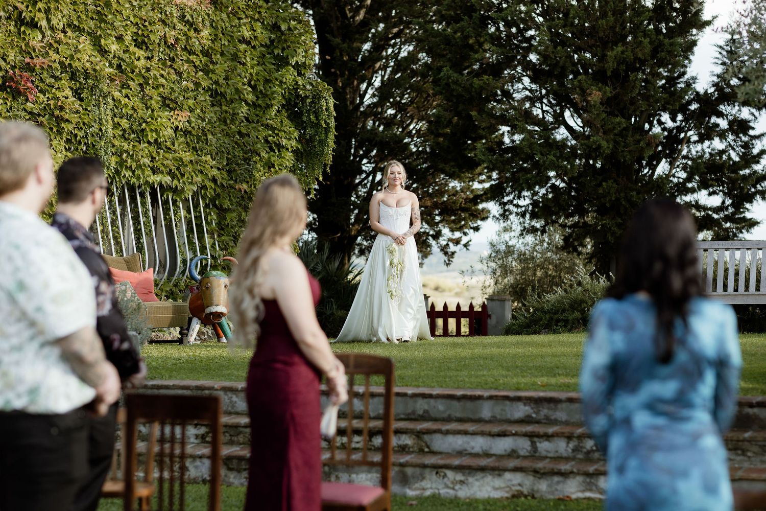 A group of people gather outdoors in a park setting for a wedding celebration.