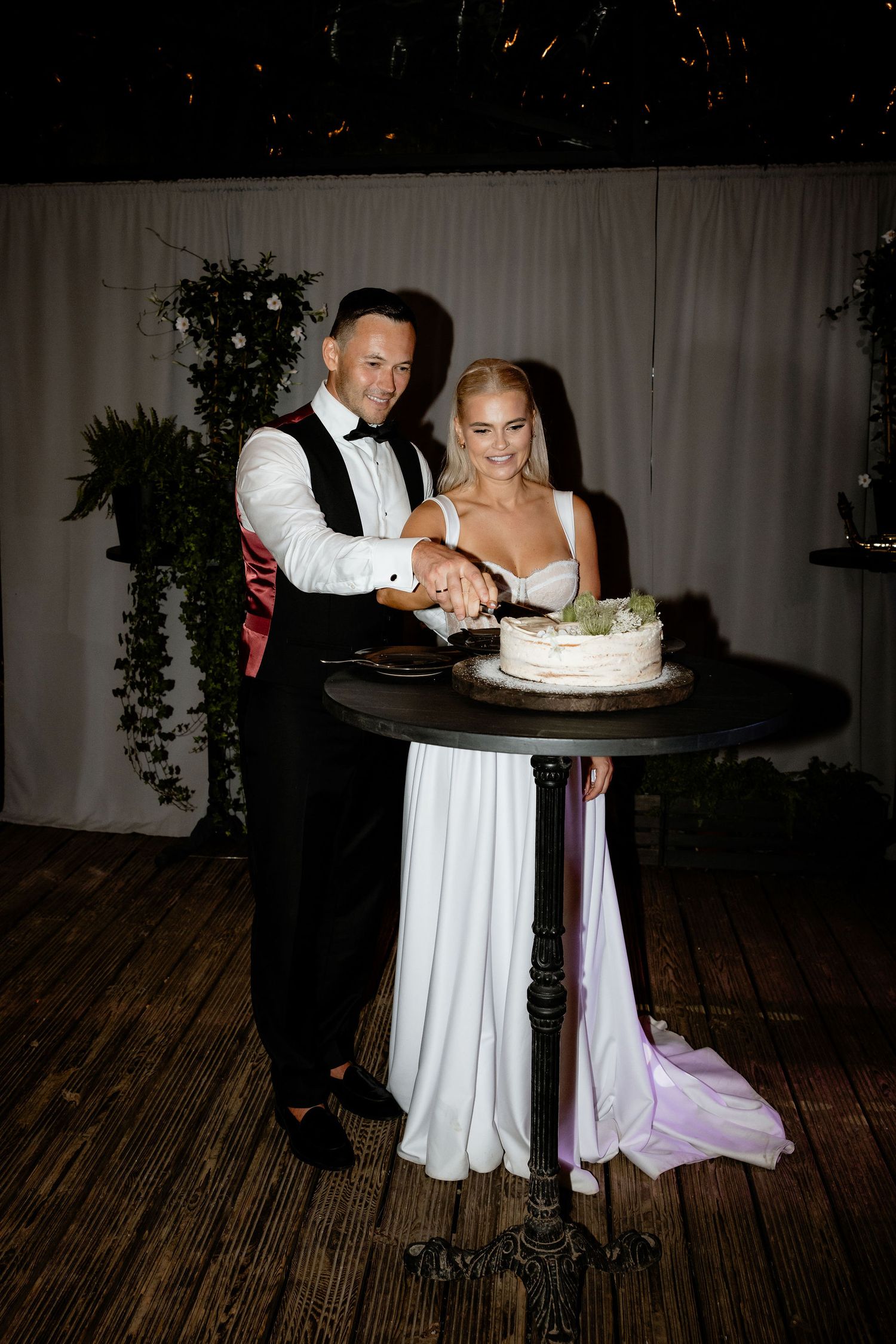 Traditional cake cutting moment at an elegant indoor wedding reception.