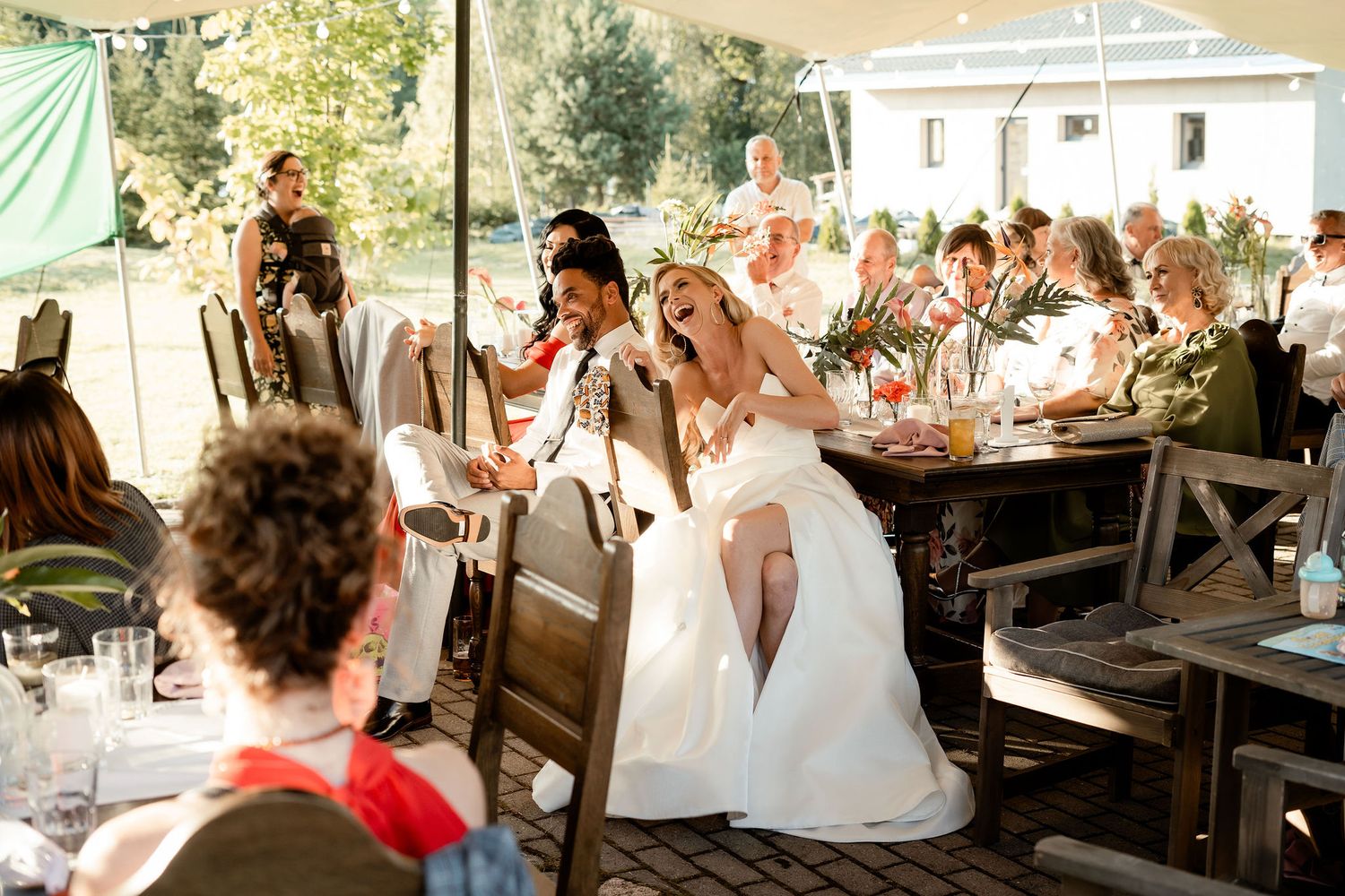 Joyful celebration during an outdoor wedding reception with rustic decor and string lights.