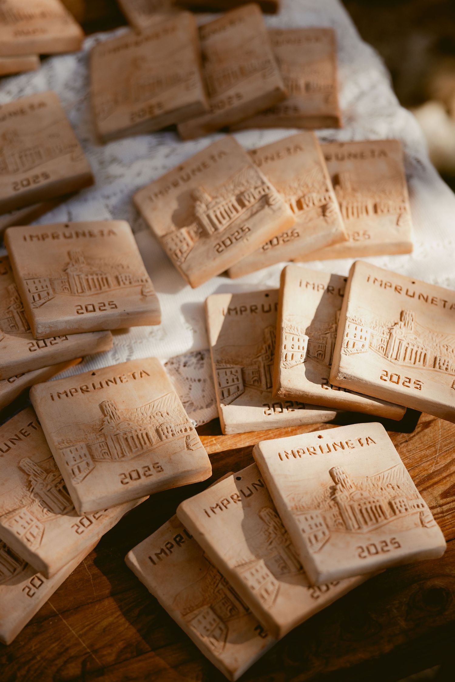 Wedding favors with architectural designs stamped into light brown clay tiles arranged on a wooden surface.