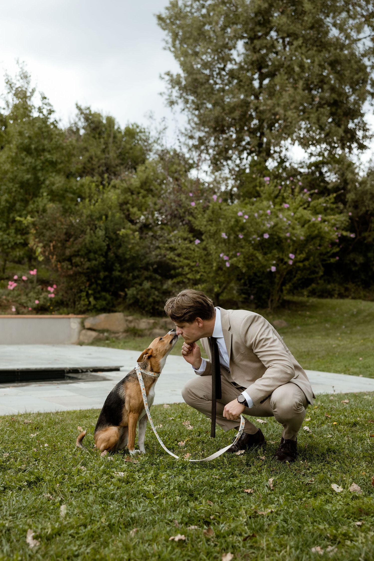 A person in beige attire plays with a beagle dog on green grass in a park setting.