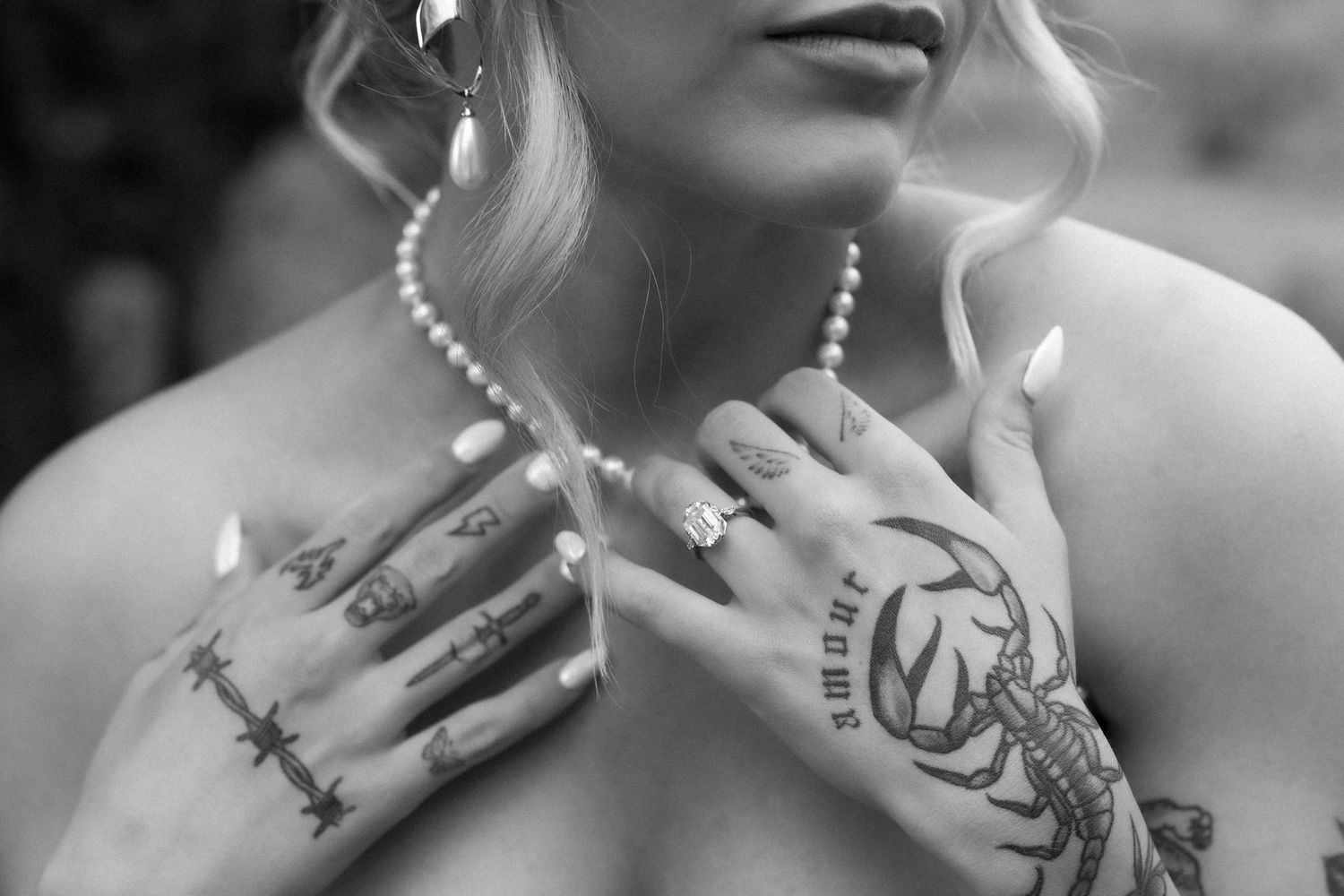 A close-up black and white portrait showing lips, neck, and jewelry details in an artistic fashion composition.