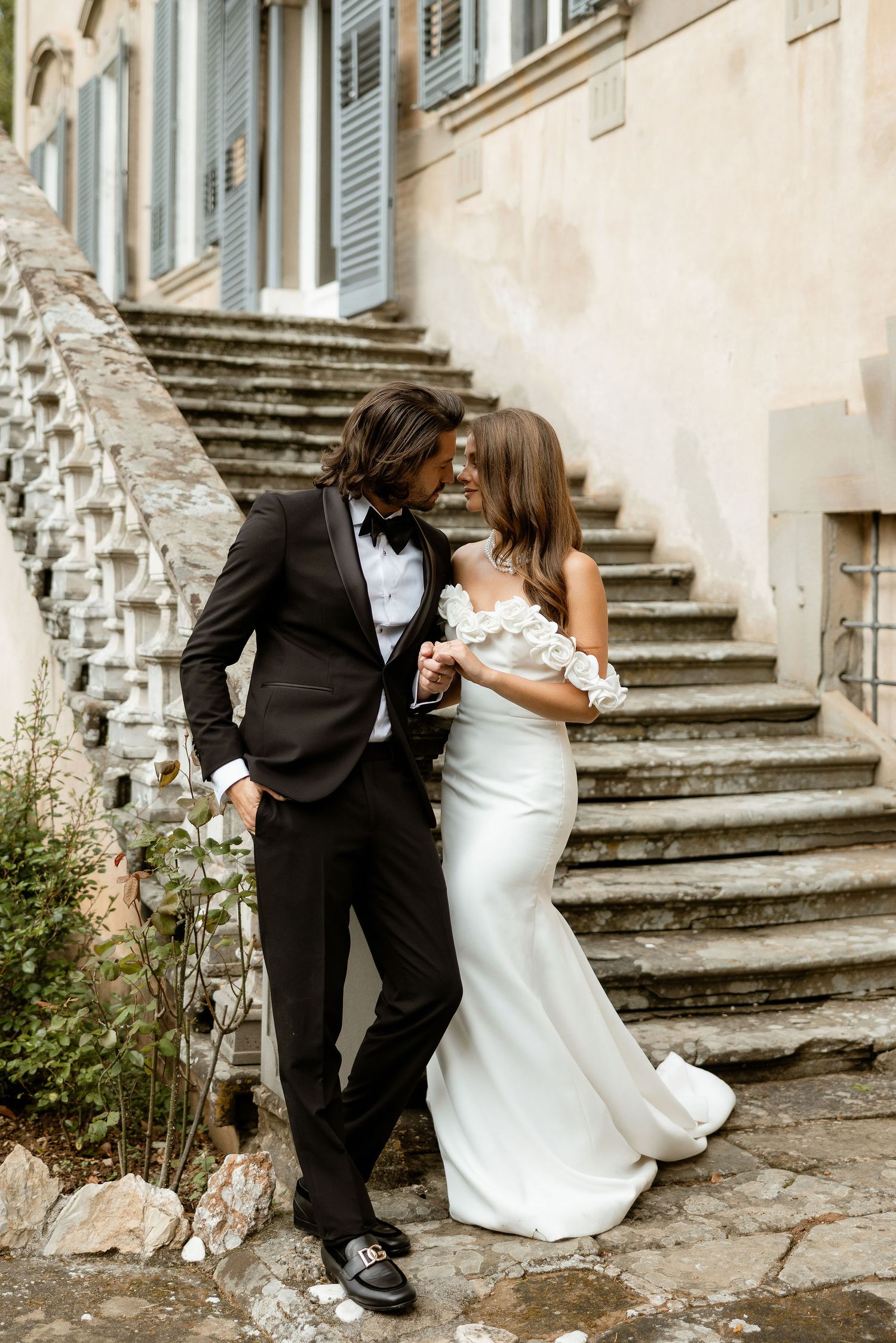 A romantic wedding couple embraces on vintage stone steps in a sequence of artistic black and white photographs.