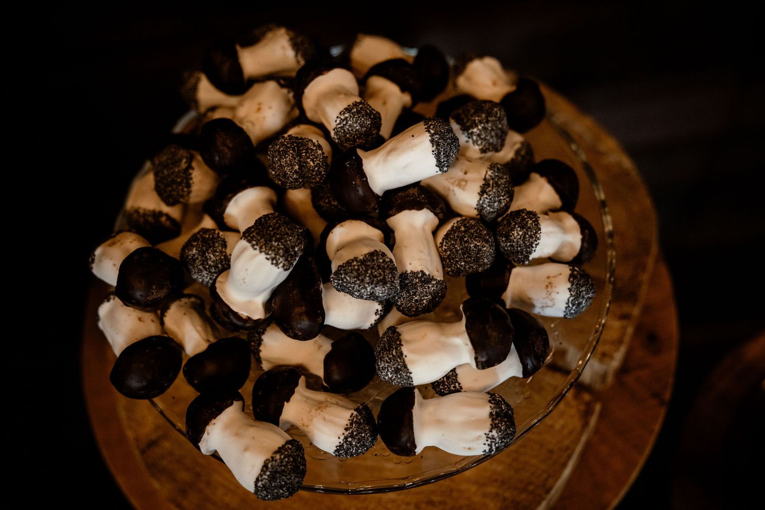 Black and white mushroom-shaped desserts arranged on a dark wooden surface.