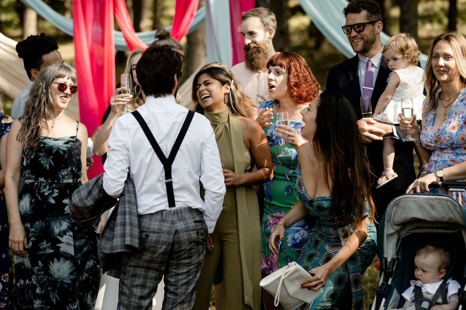 Wedding guests socialize during outdoor reception with colorful fabric decorations.