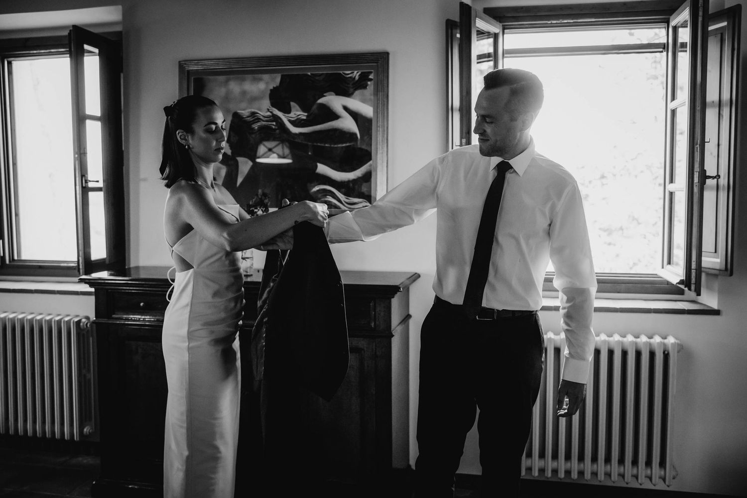 Black and white candid capture of wedding day preparations in a sunlit room.