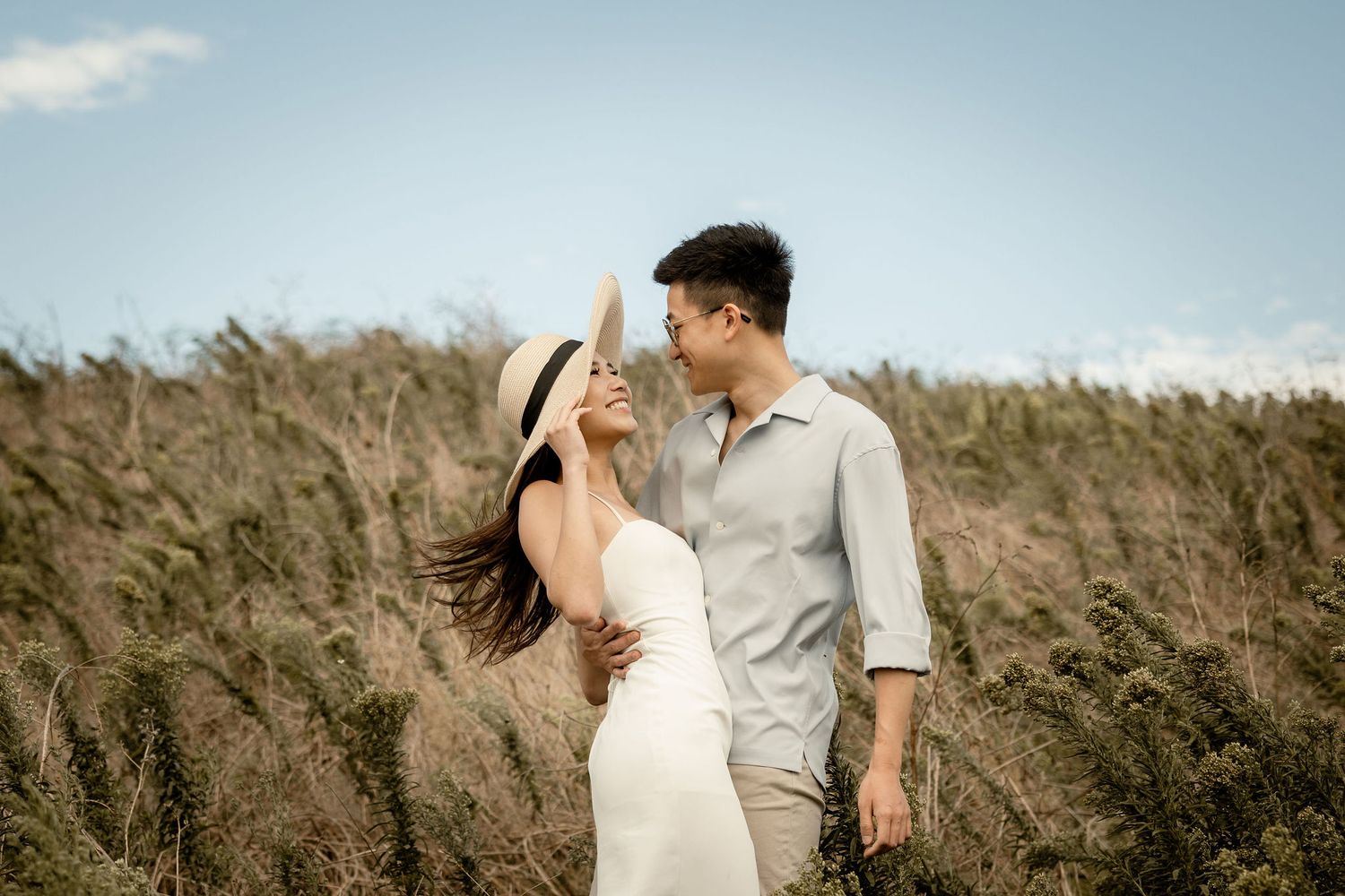 A couple shares an intimate moment in a field of tall grass.