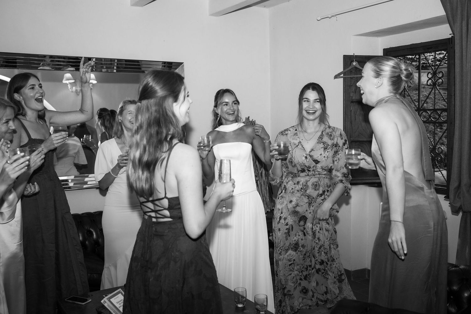 A black and white photo collage showing a wedding celebration with people dancing, hugging and mingling at a reception.