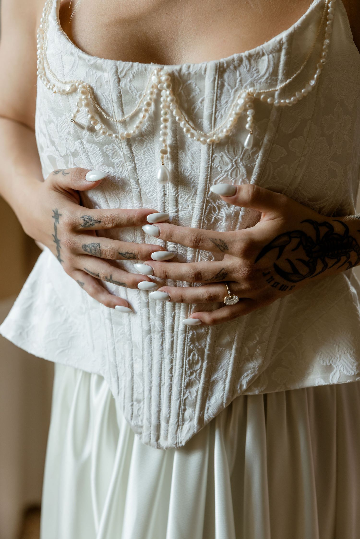 Close-up view of hands resting on a white lace corset bodice of a vintage-style dress.