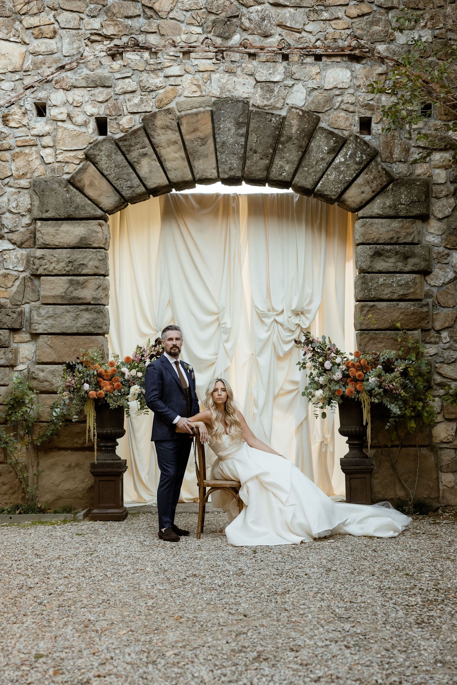 Wedding couple poses against rustic stone wall with white curtains and floral arrangements in three sequential photos.