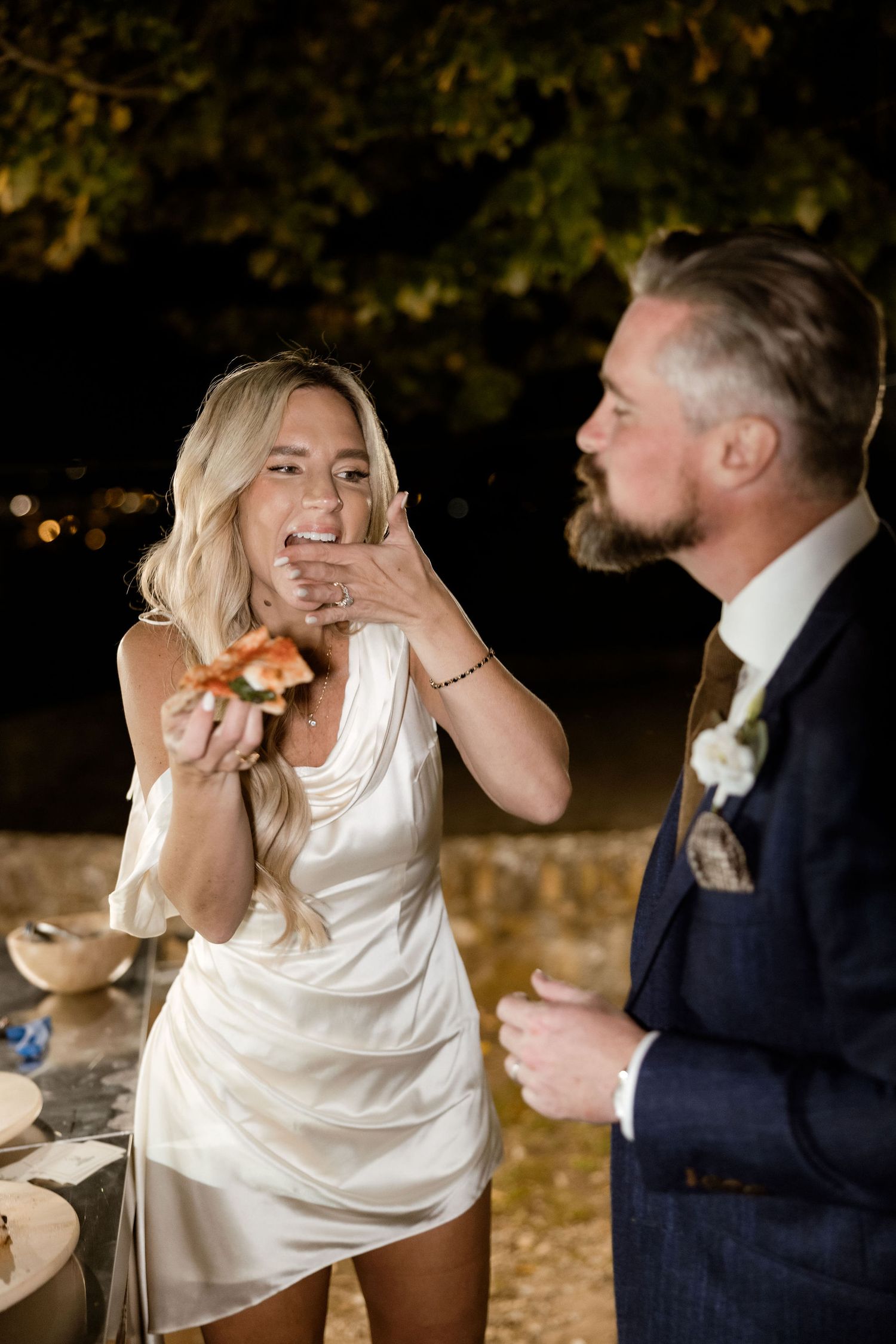 A couple shares a playful moment during their wedding reception as the bride laughs with her hand over her mouth.