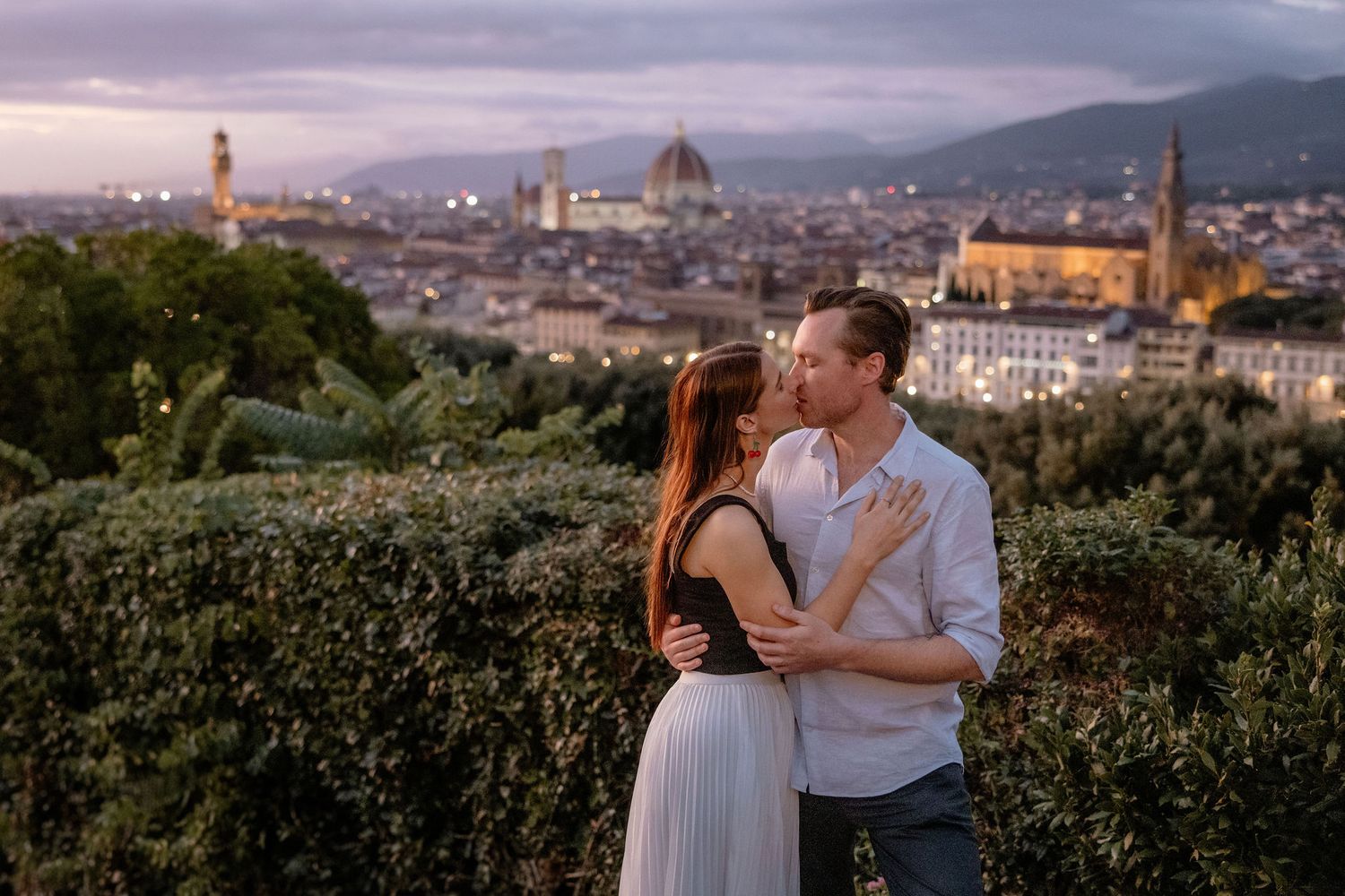 A romantic couple embraces at sunset overlooking the stunning Florence skyline with the Duomo cathedral in Italy.