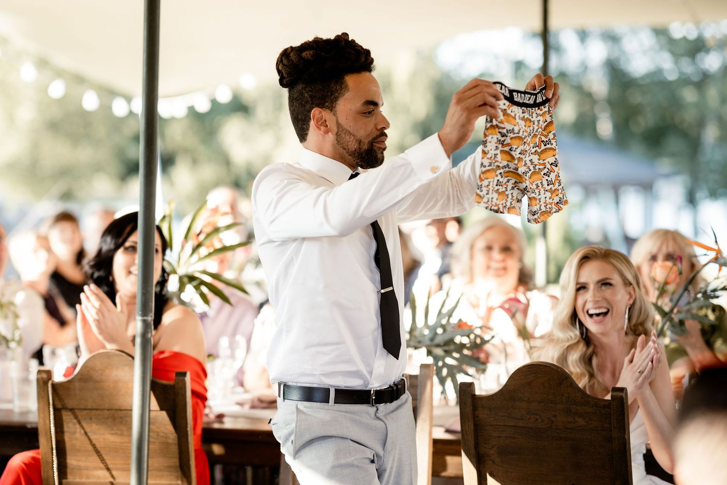 A celebratory moment during a wedding reception with guests cheering under a tent.