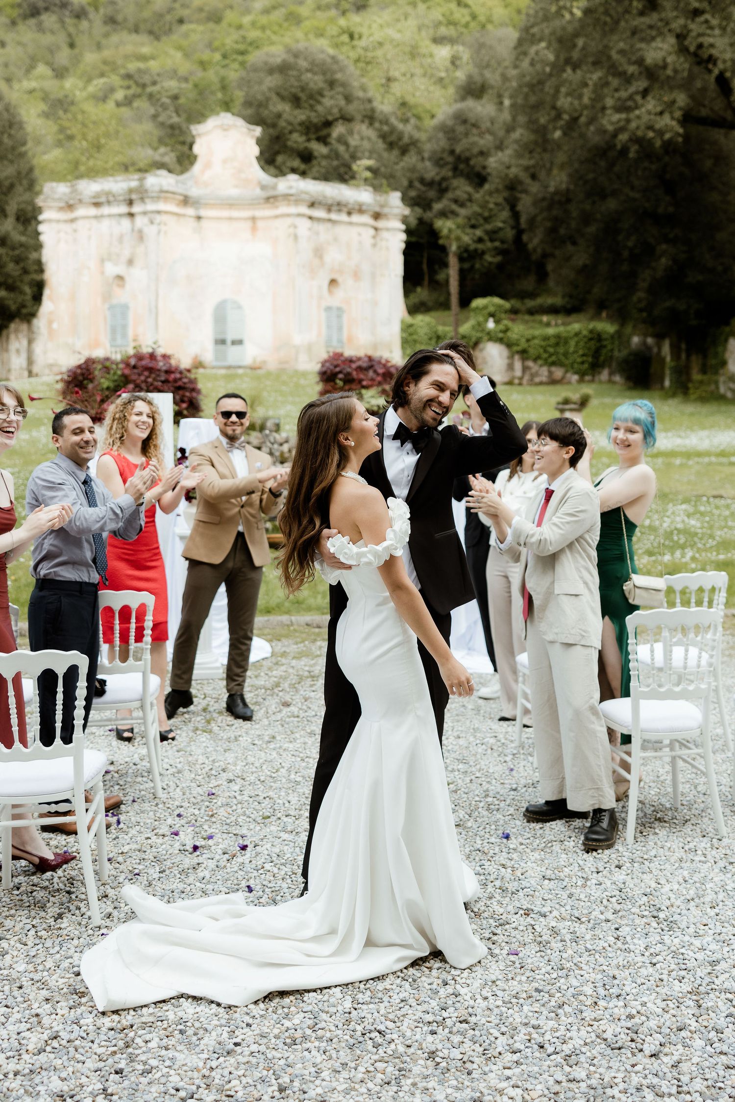 Outdoor wedding celebration with guests and couple dancing on gravel with historic domed building in background.
