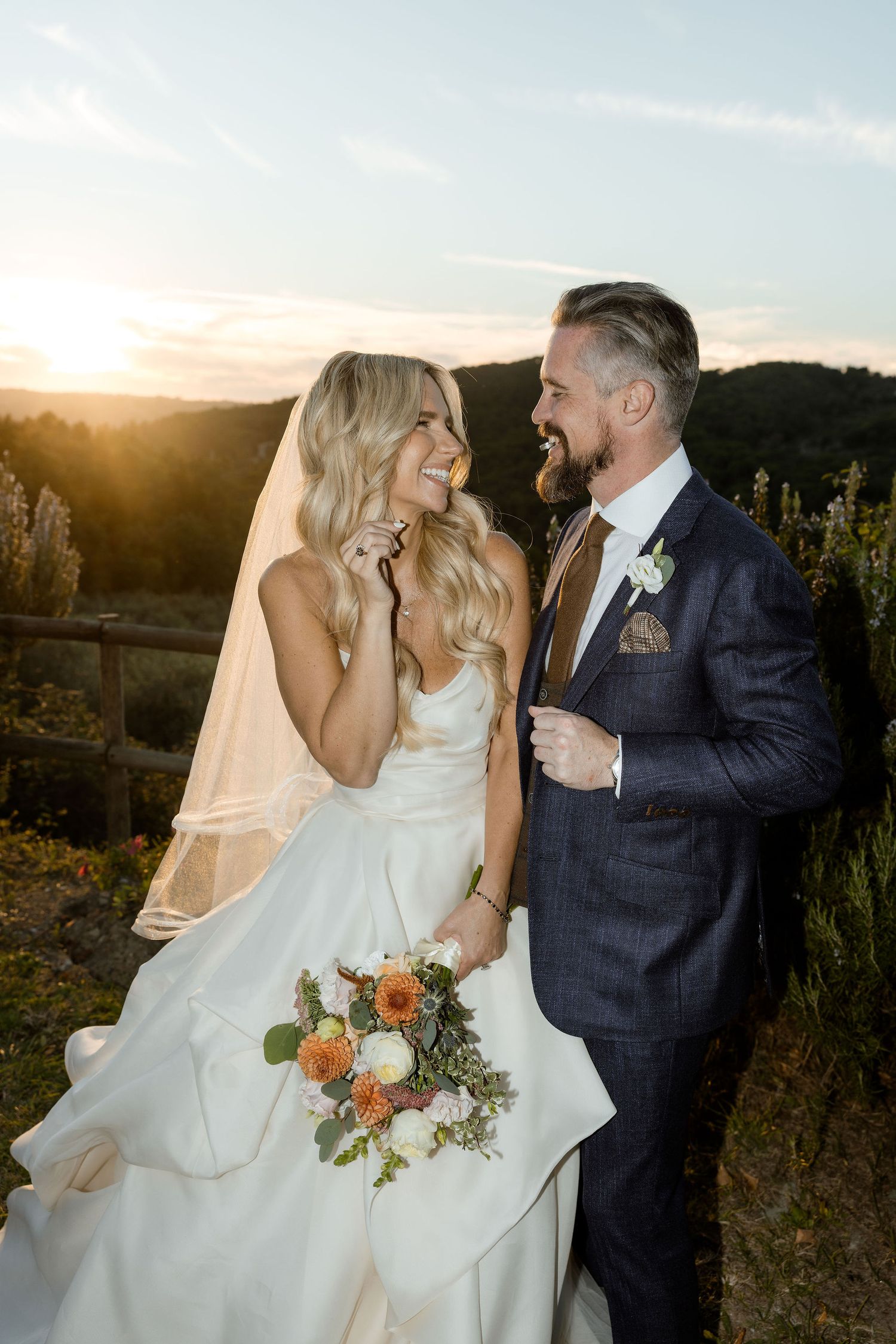 A wedding couple shares intimate moments during sunset in an outdoor setting with warm golden light.