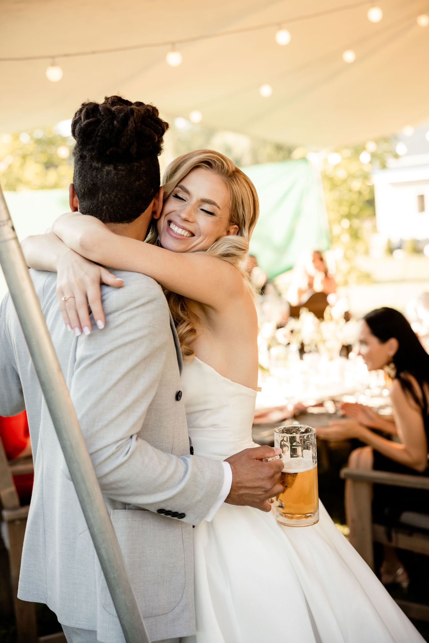 A joyful embrace between newlyweds during their outdoor reception celebration.