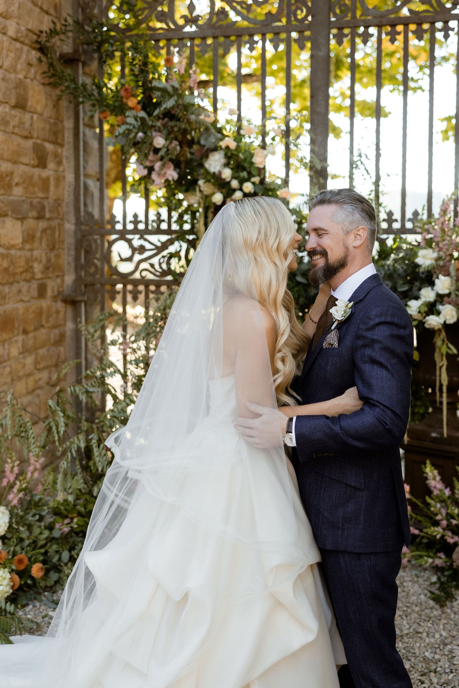 A romantic wedding sequence shows a couple sharing their first kiss under an elegant stone archway with floral decorations.