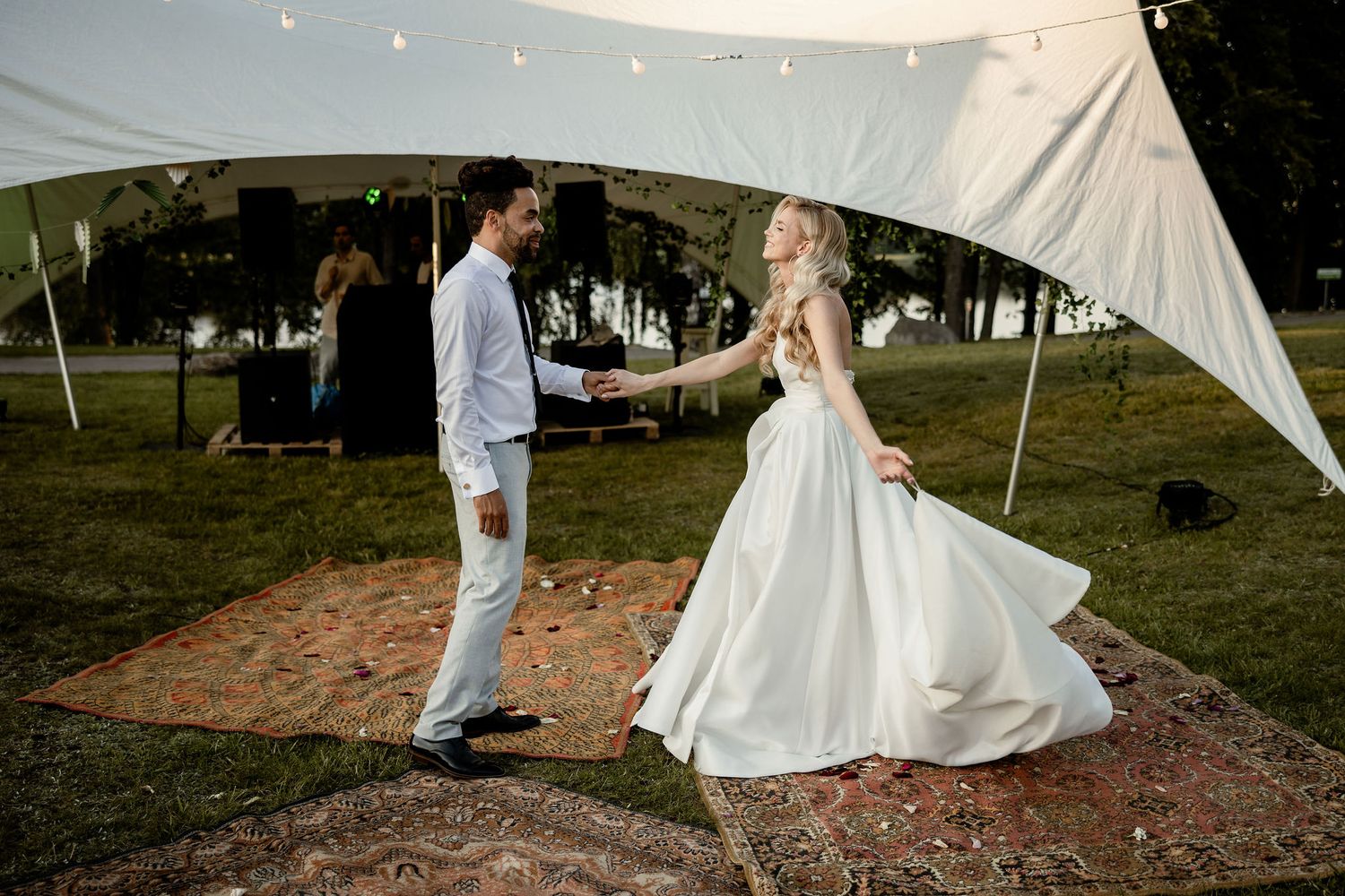 A romantic moment between newlyweds dancing beneath a white outdoor wedding tent.