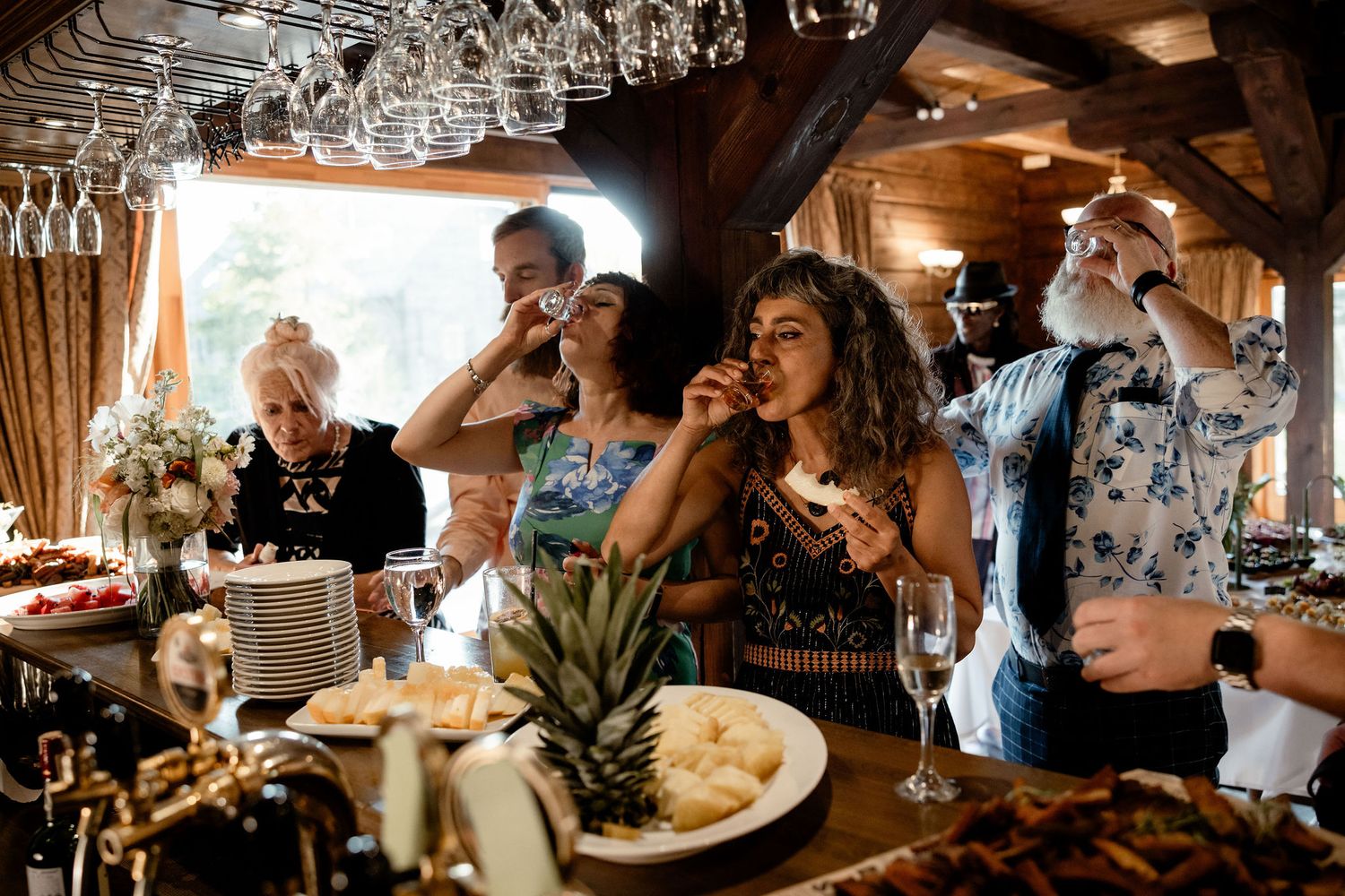 Wedding guests enjoying drinks and food at rustic indoor reception venue.