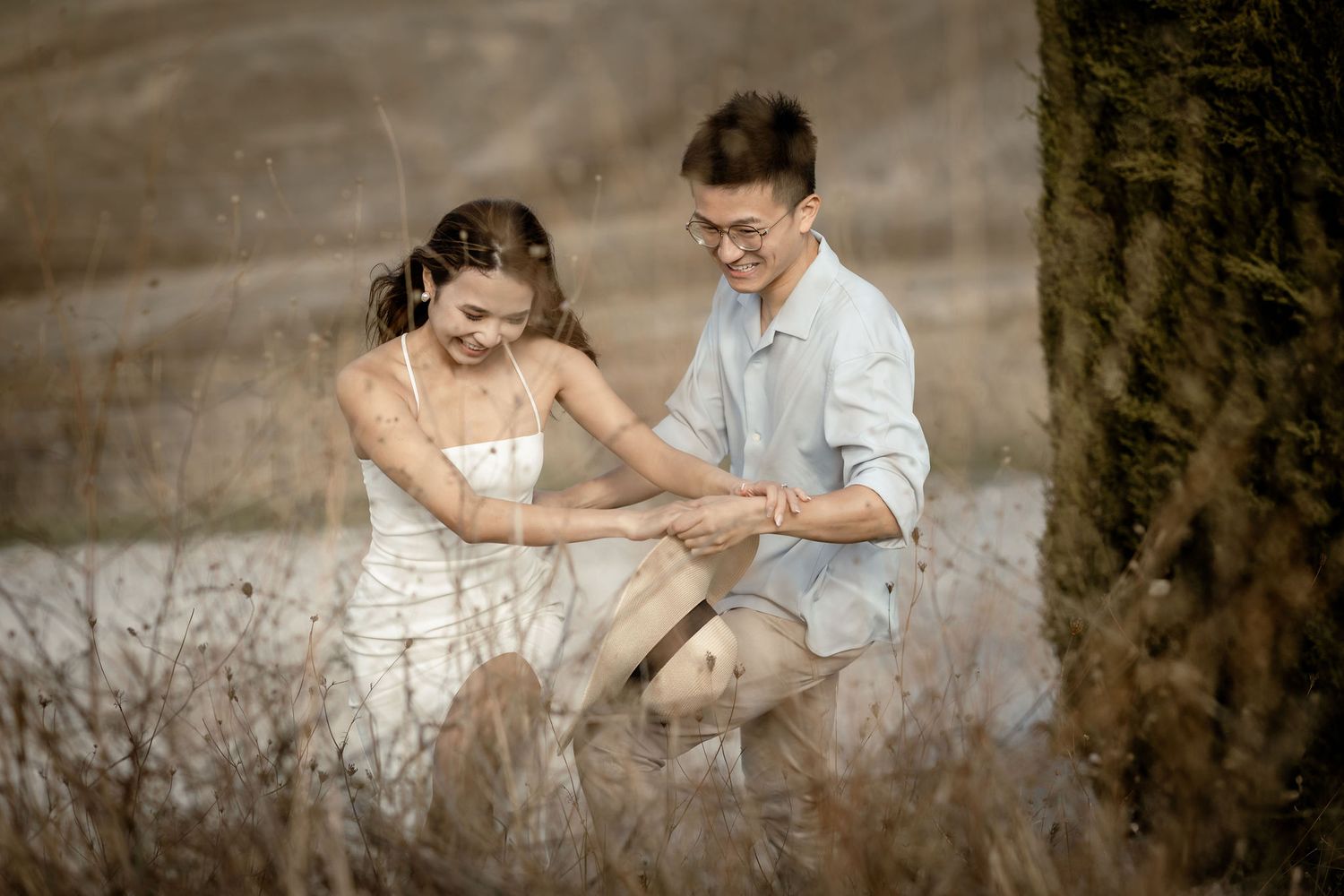Playful couple sharing lighthearted moment on rural path with cypress trees.