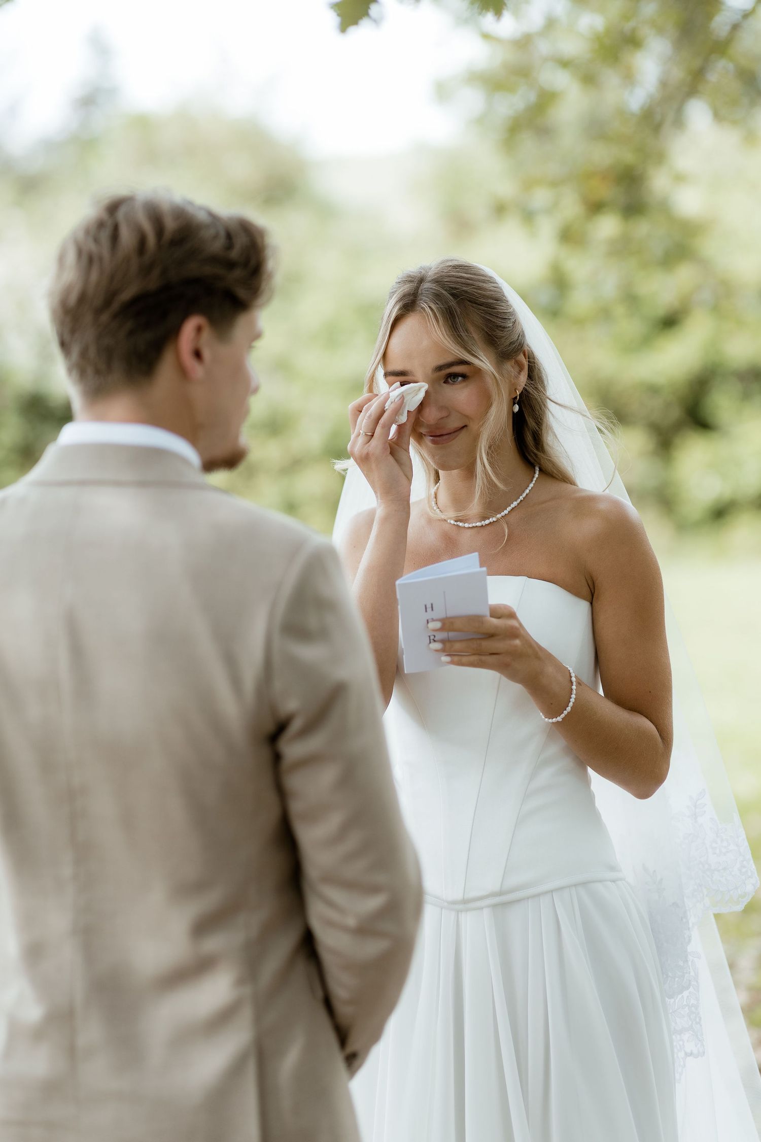 A couple shares an emotional moment during their first look at an outdoor wedding ceremony.