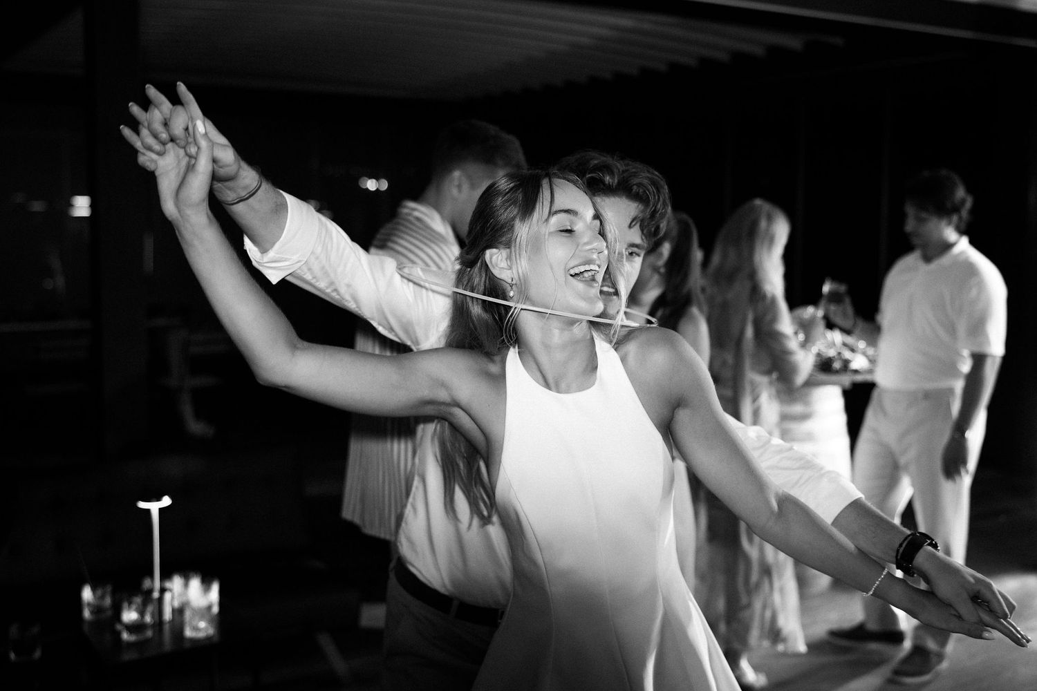People dancing and celebrating at a dimly lit indoor venue with festive atmosphere.