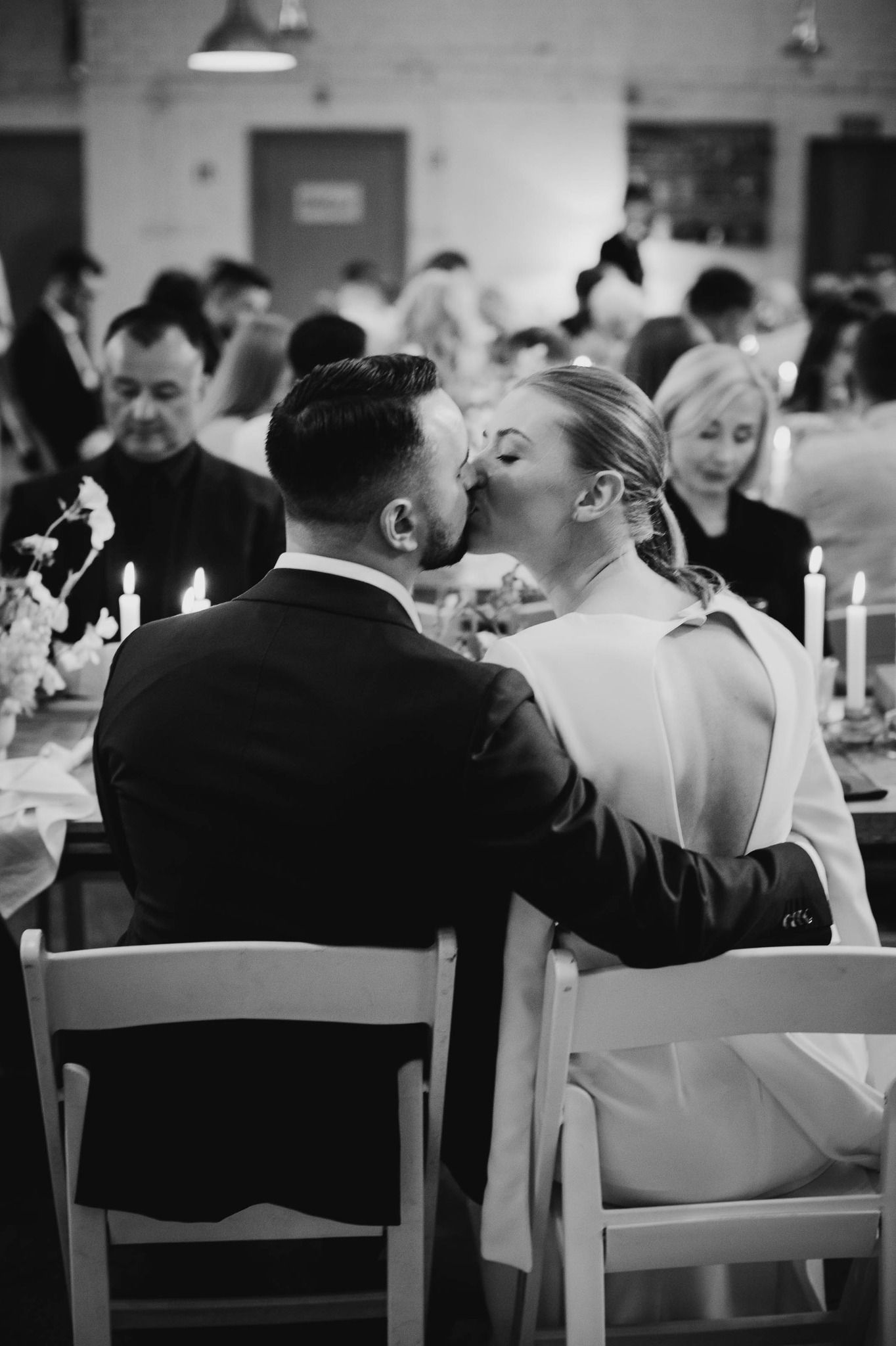 Black and white photo of wedding guests sitting at tables during a reception celebration.