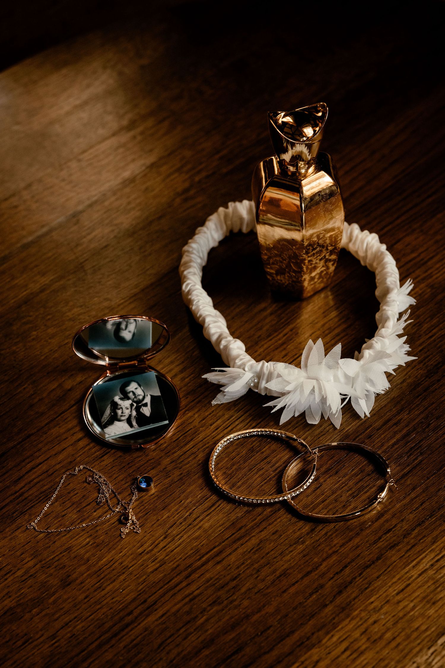 Wedding accessories including floral crown and jewelry on dark wooden surface.