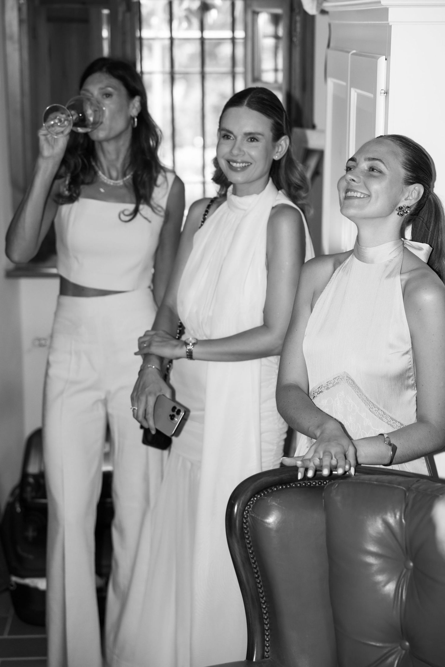 Group of people in white dresses and outfits laughing and having fun at an indoor event.
