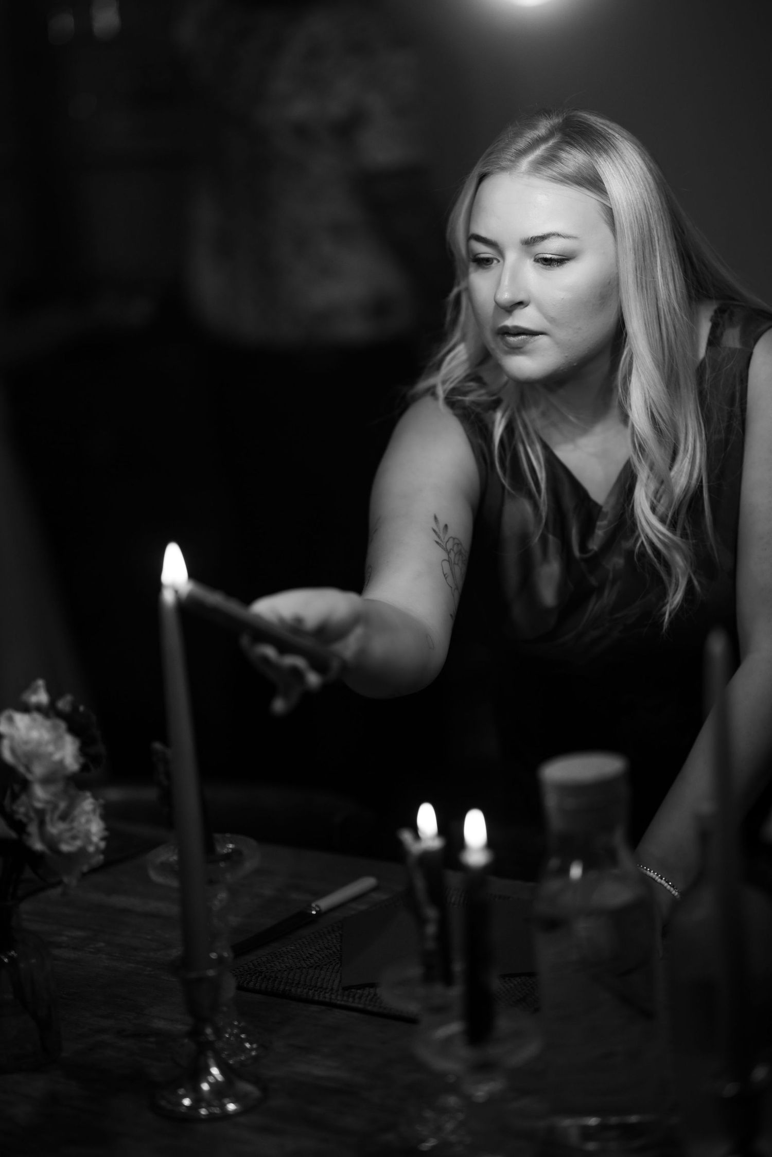 A series of black and white photos showing someone blowing out candles on a dark table with dramatic lighting.