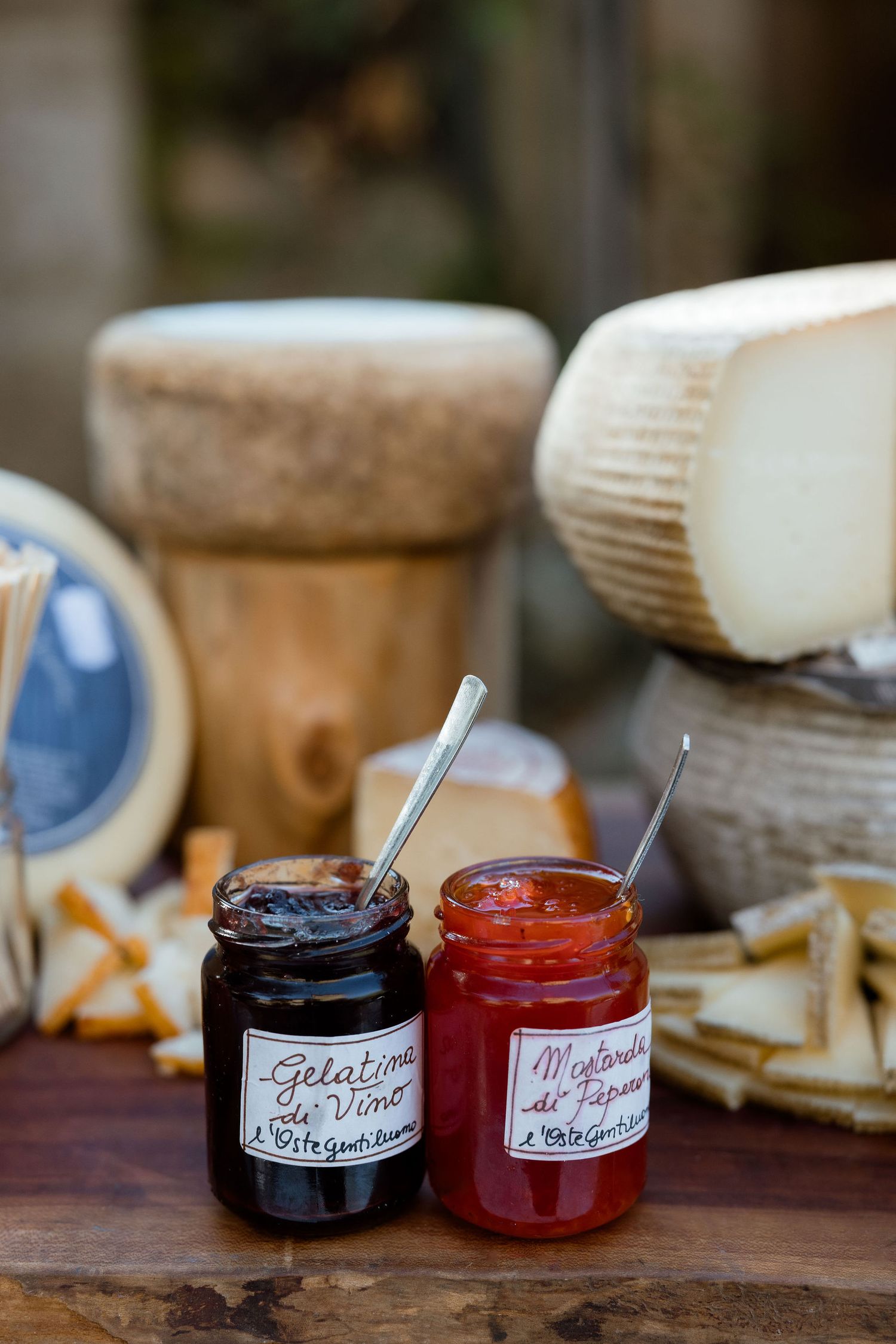 Small jars of homemade preserves and jams in dark blue and red colors displayed on a rustic wooden surface.
