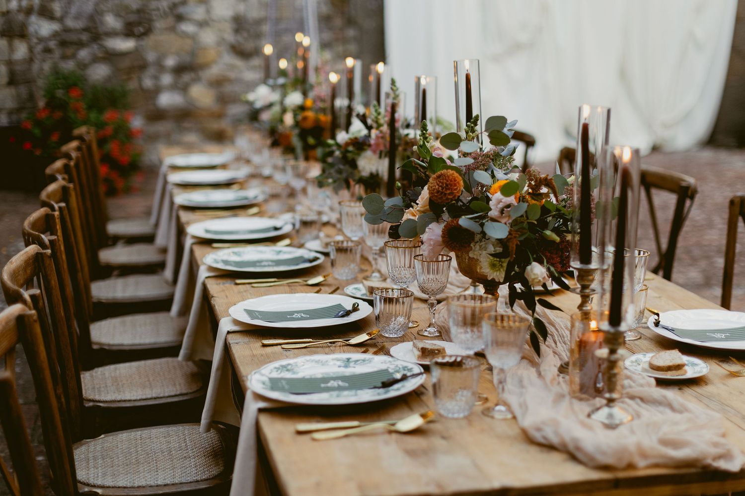 An elegant rustic wedding table setting with candles, floral arrangements and place settings in warm earth tones.