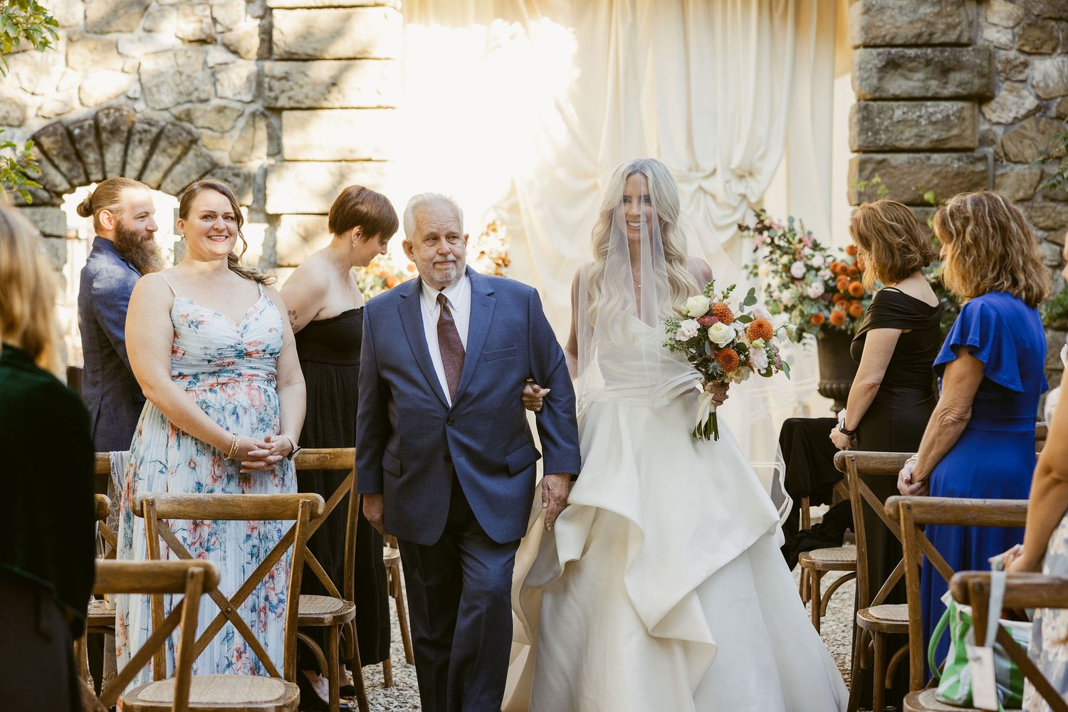 Elegant wedding ceremony setup with wooden chairs and floral arrangements in a rustic outdoor venue.