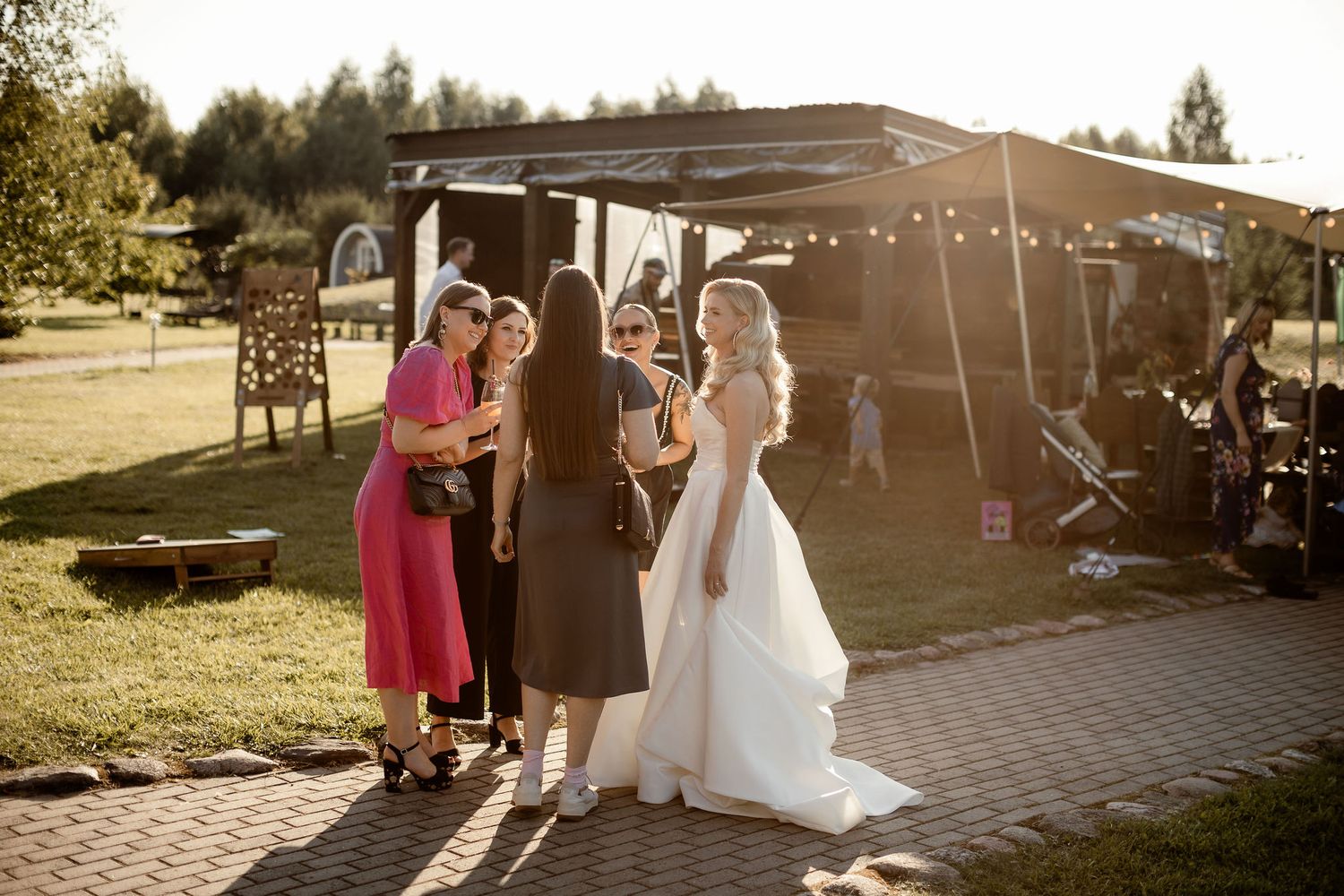 Wedding party poses together during golden hour under an outdoor tent.