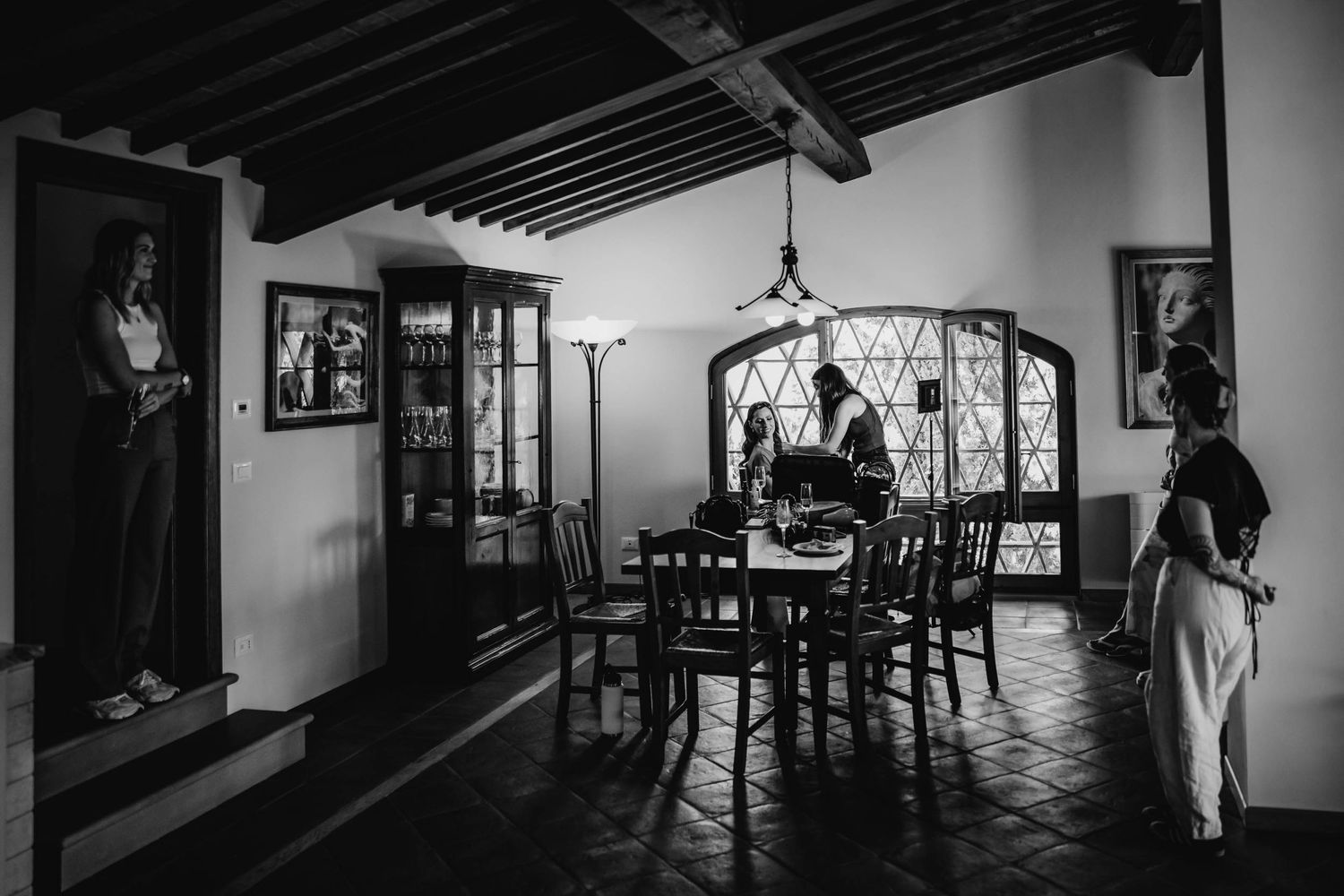 Black and white interior shot of vintage dining room with beam ceiling and ornate decor.