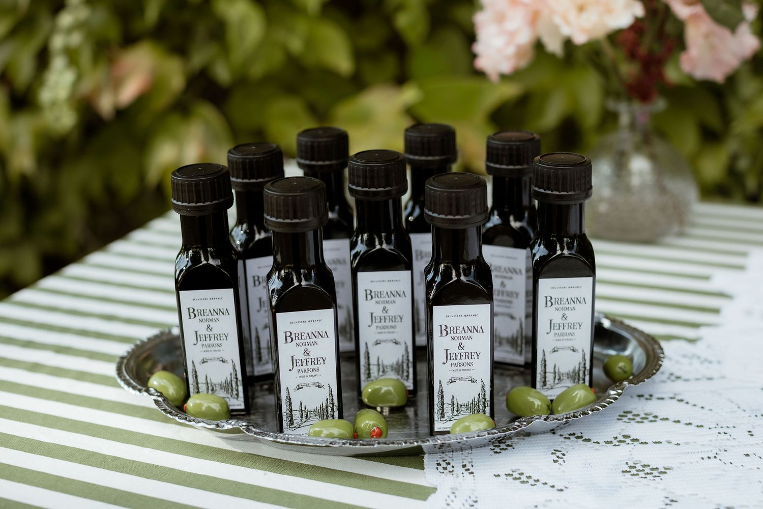 Small bottles of black ink arranged in rows on a striped tablecloth at an outdoor event display.