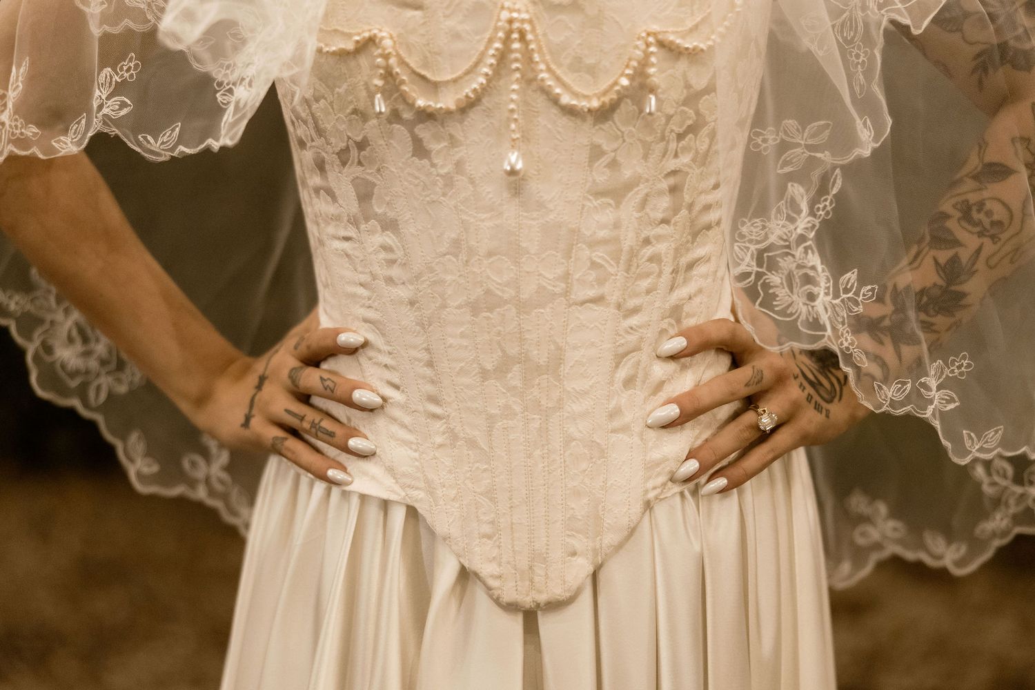 Close-up details of delicate white lace and embroidery on a vintage-style wedding dress.
