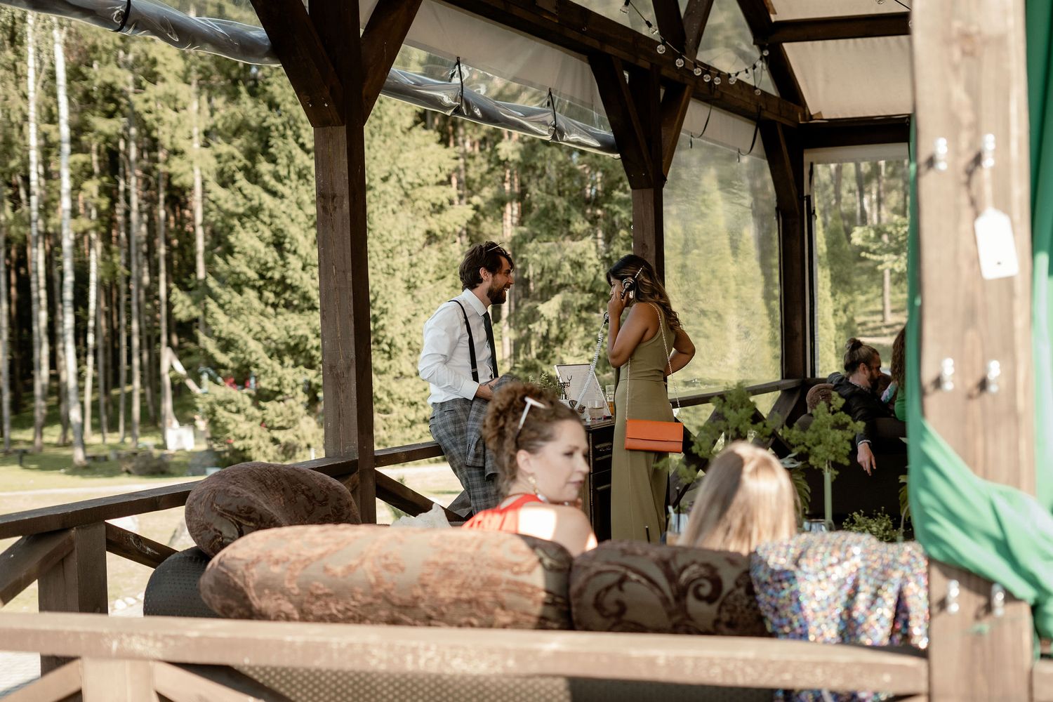 People relaxing on a covered outdoor patio with forest views.