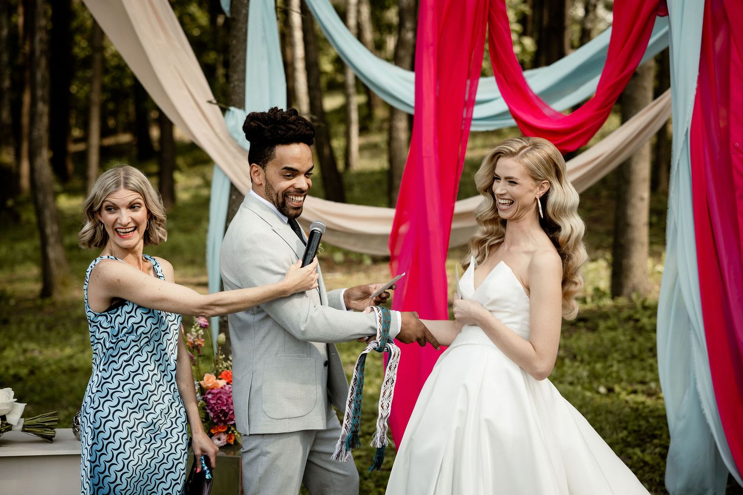 A joyful wedding ceremony moment under draped fabric decorations in a forest setting.
