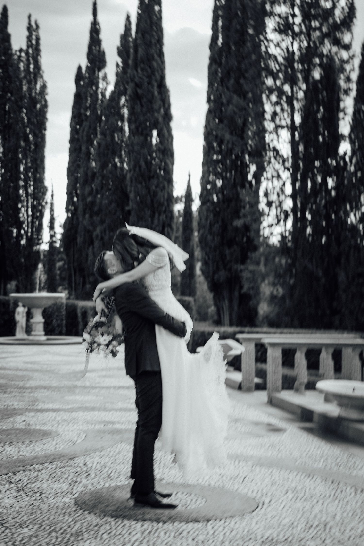Romantic lift pose among cypress trees in black and white.
